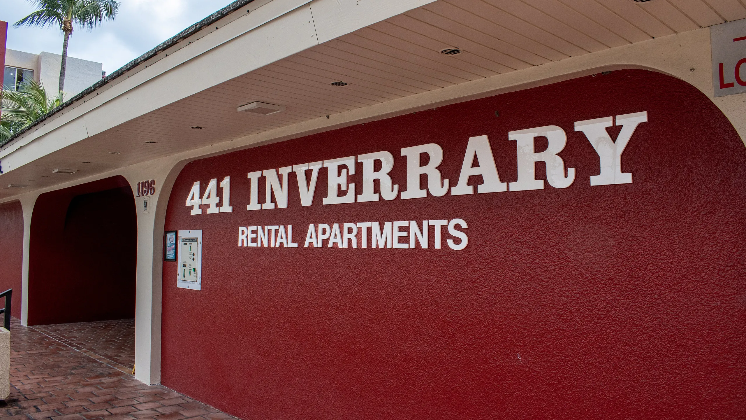 Welcome to 441 Inverrary Rental Apartments, featuring a vibrant red fa&ccedil;ade and inviting entrance.
