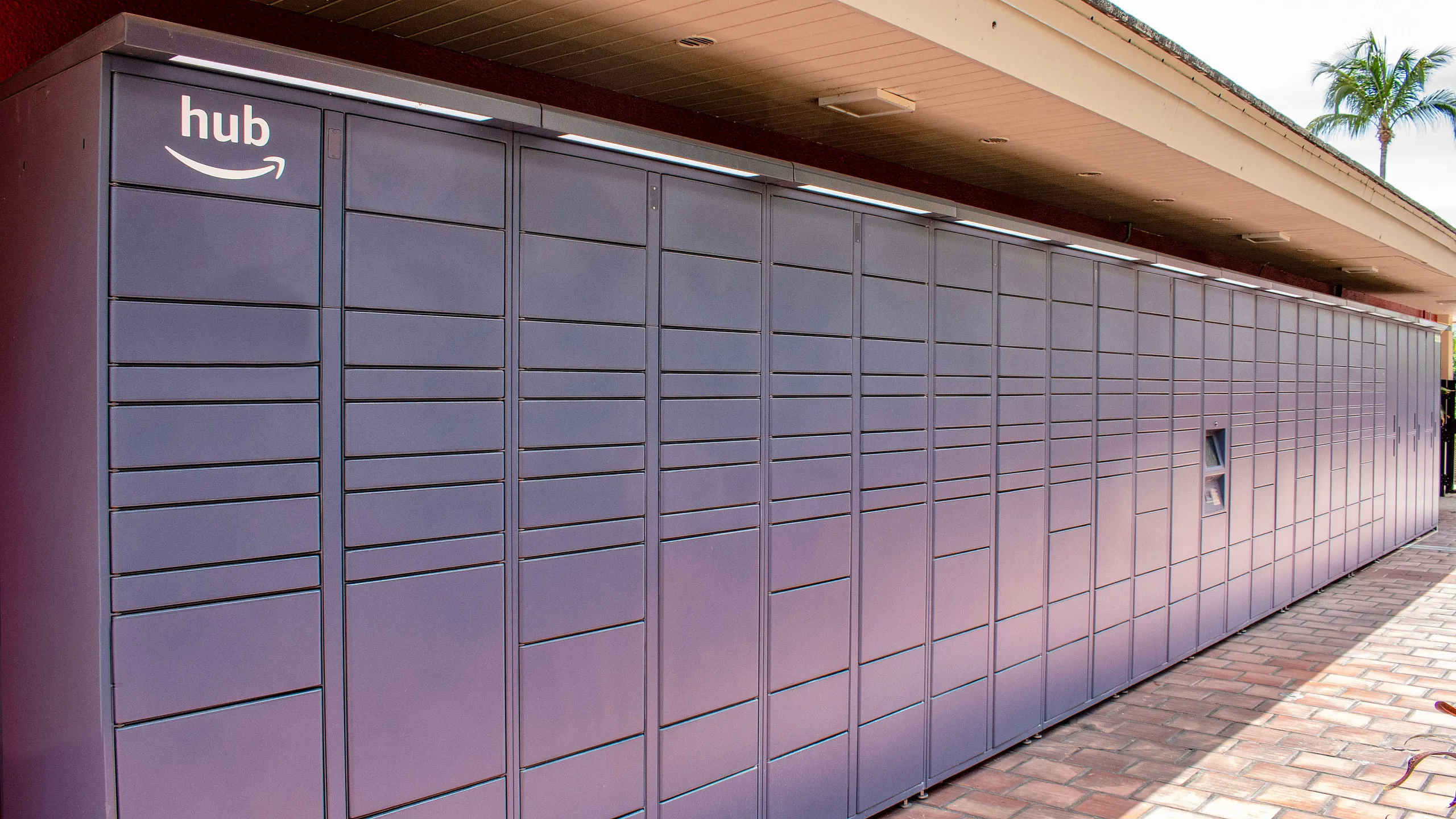 Modern apartment complex with secure parcel locker system under a covered walkway, featuring sleek design and convenient access.