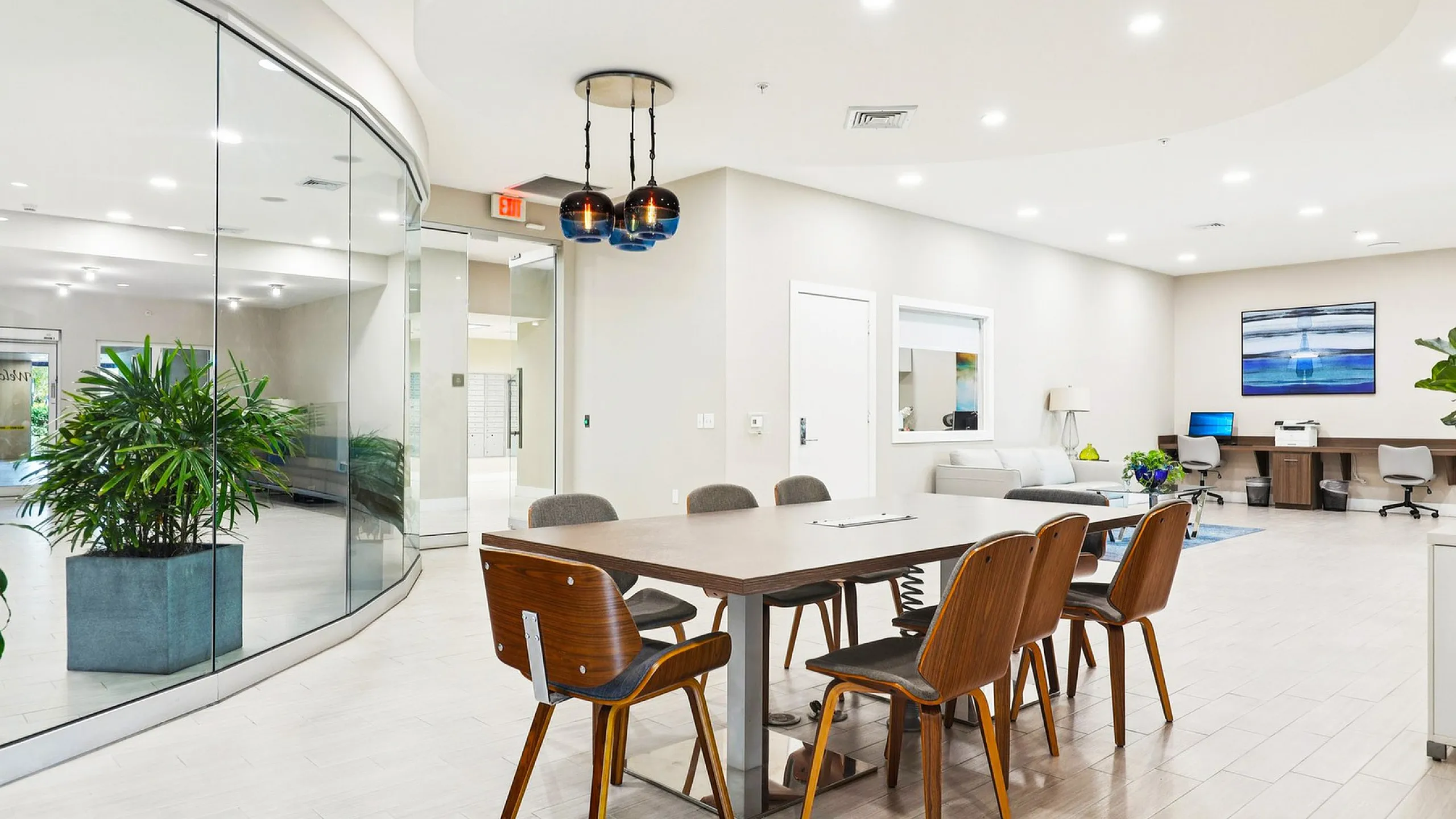 Elegant and modern office space with chic wooden chairs, a spacious meeting table, and large curved glass walls offering a view of lush indoor plants.