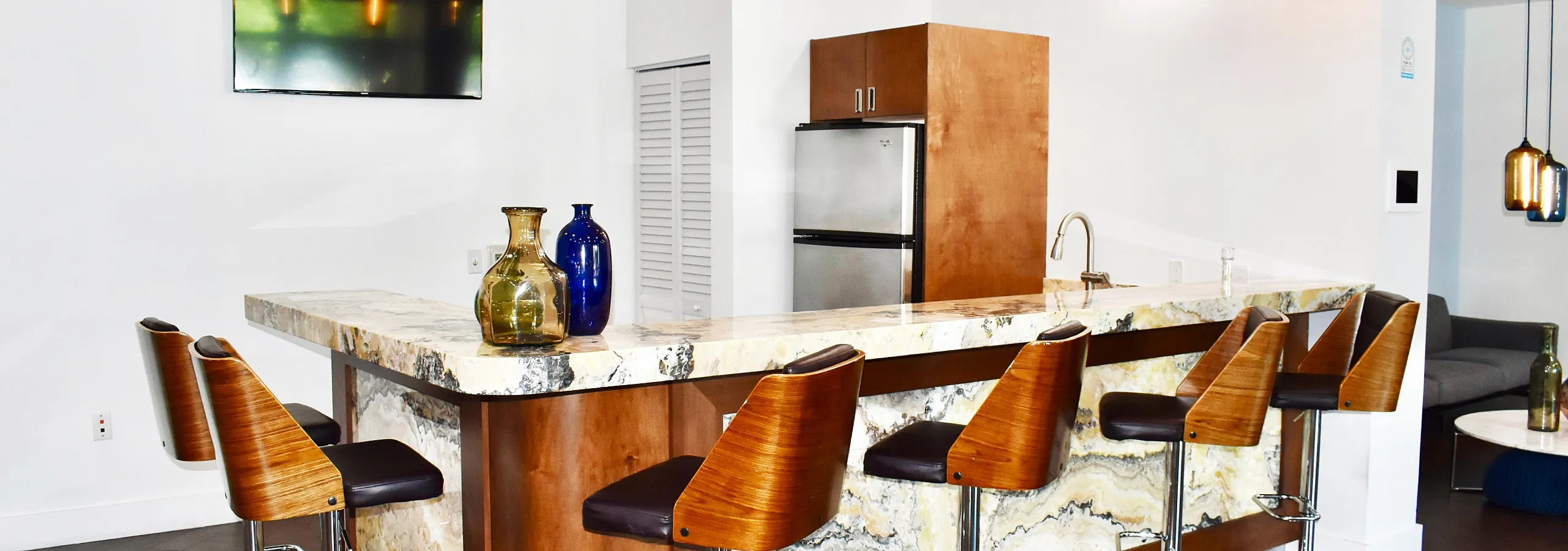 Elegant modern kitchen with marble bar countertop, stylish bar stools, and striking pendant lighting.