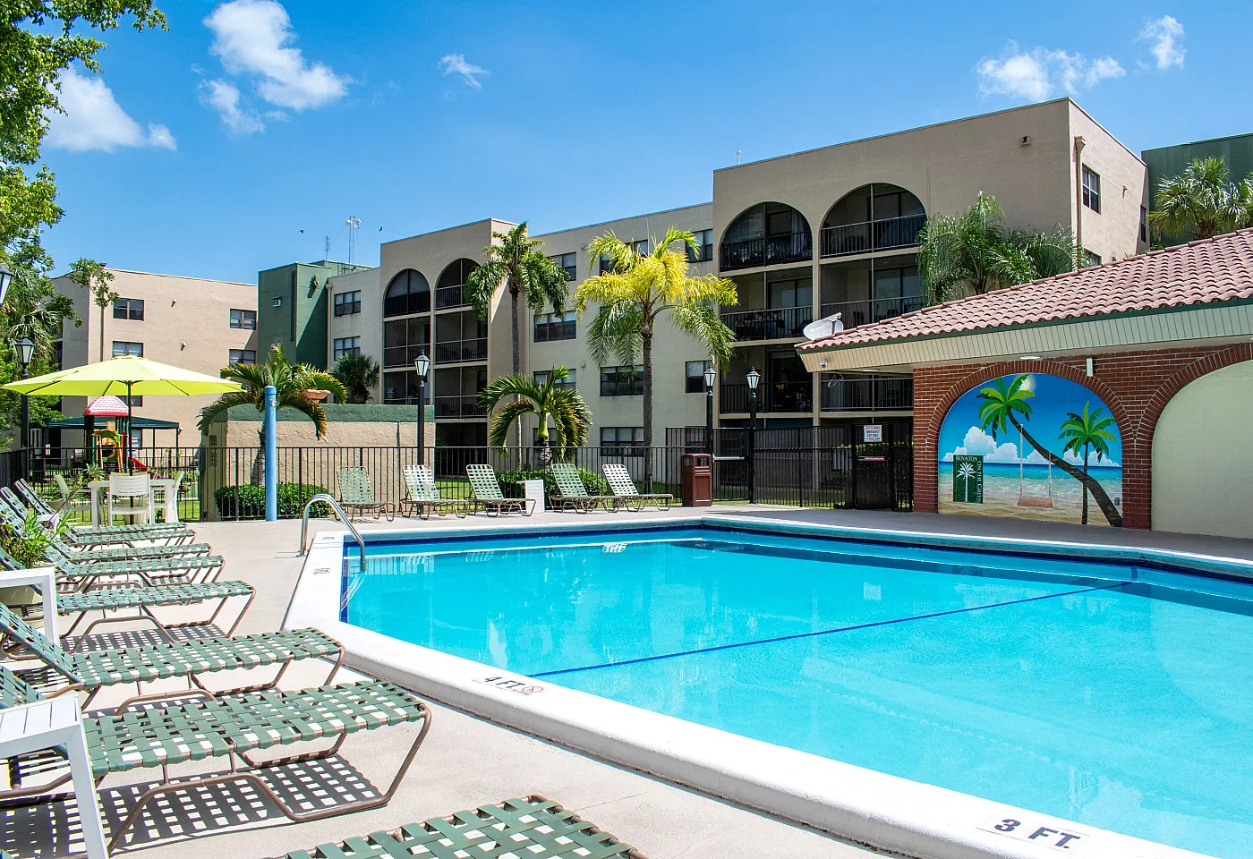 Inviting apartment complex pool area with comfortable sun loungers and vibrant mural, perfect for relaxation and enjoyment.