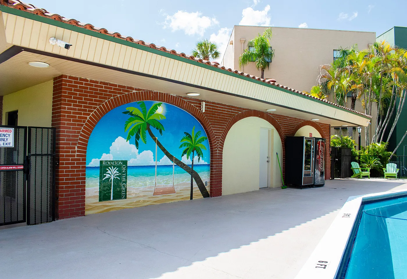 Vibrant poolside area with a tropical mural, palm trees, and lounge chairs, offering a serene escape.