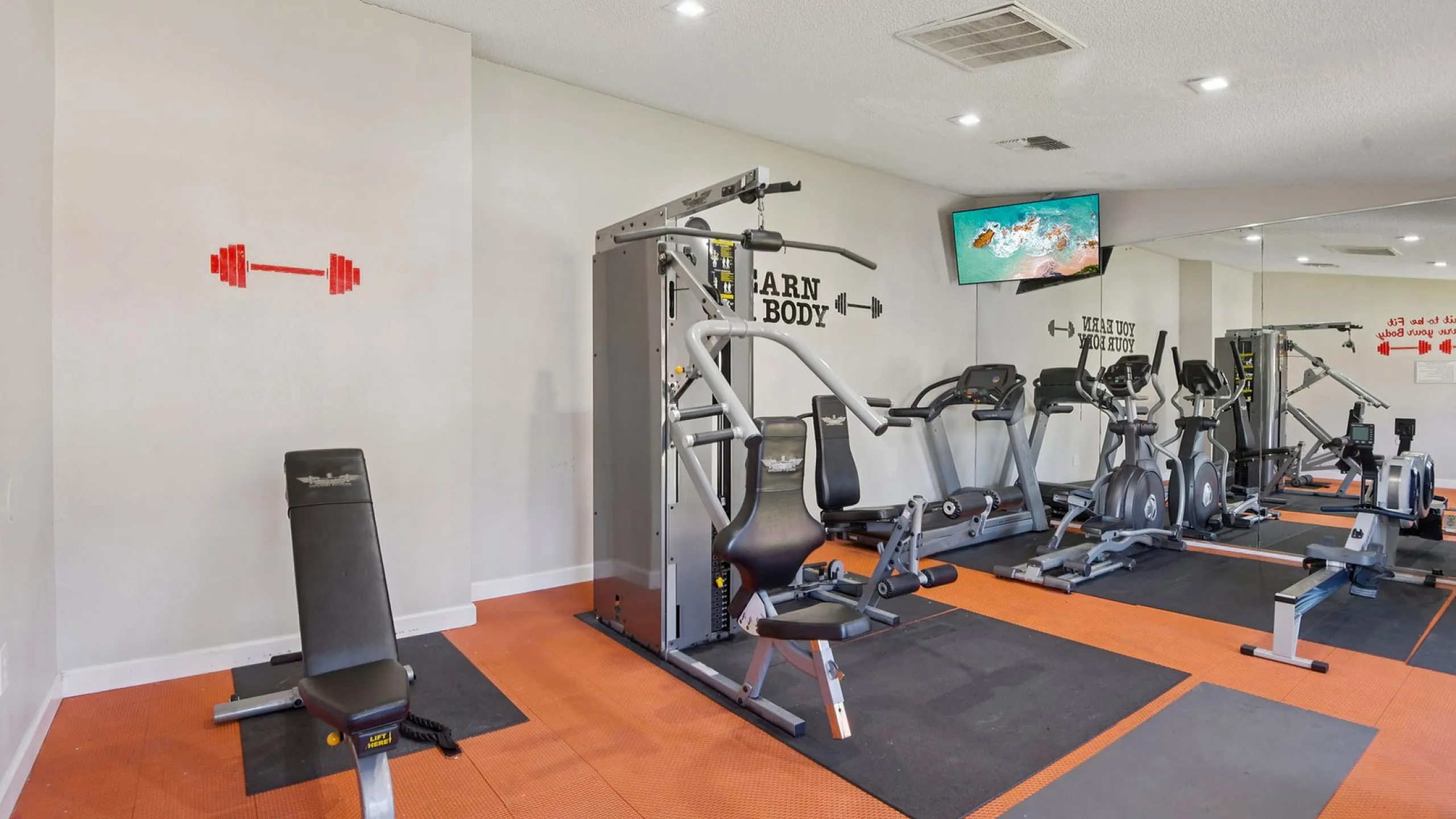 Modern fitness center equipped with state-of-the-art exercise machines and vibrant orange flooring, designed for a dynamic workout experience.