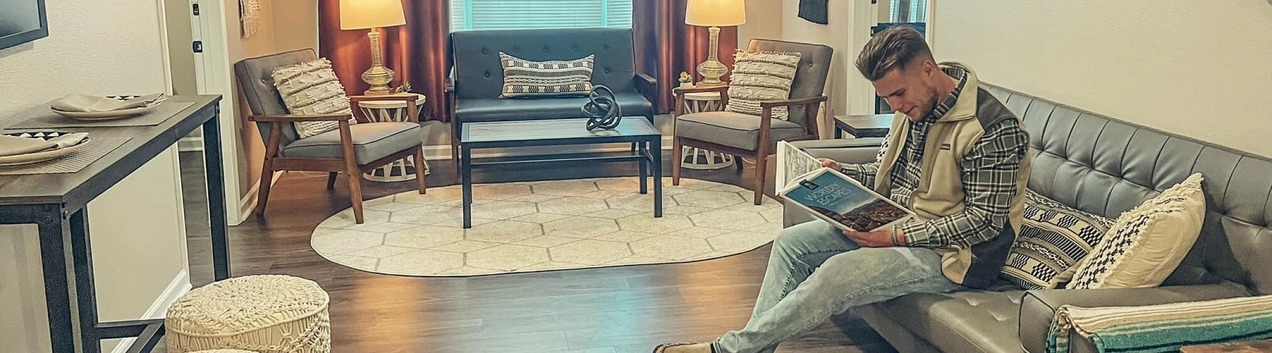 the view student apartments living space with male student reading a coffee table book