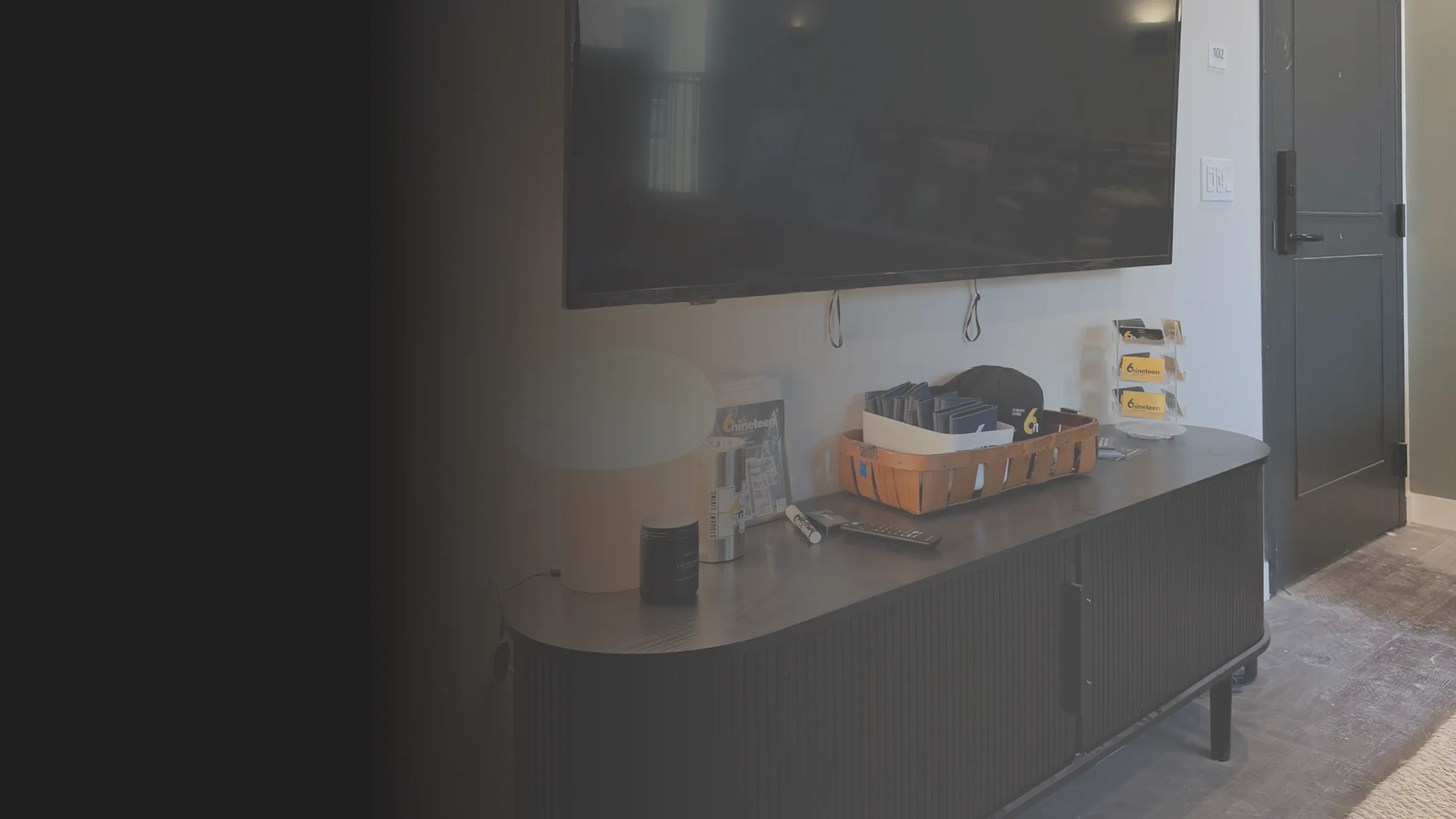 tv console with 6nineteen merchandise, tv mounted on wall above.