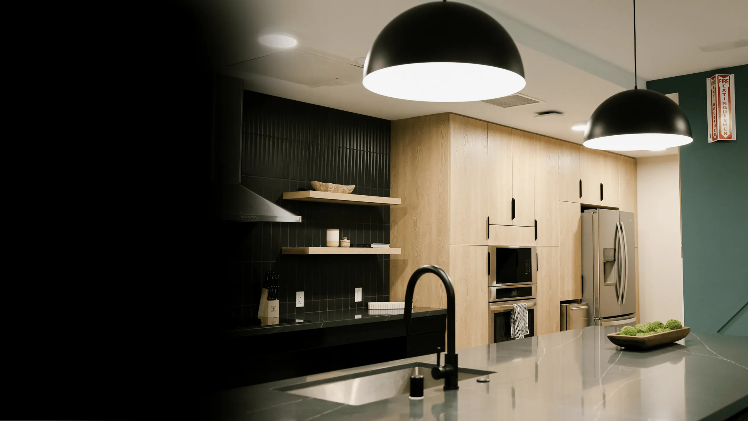 Modern kitchen featuring wood-paneled cabinetry, stainless-steel appliances, and a large quartz island with pendant lighting, highlighting a stylish amenity space ideal for contemporary apartment living.