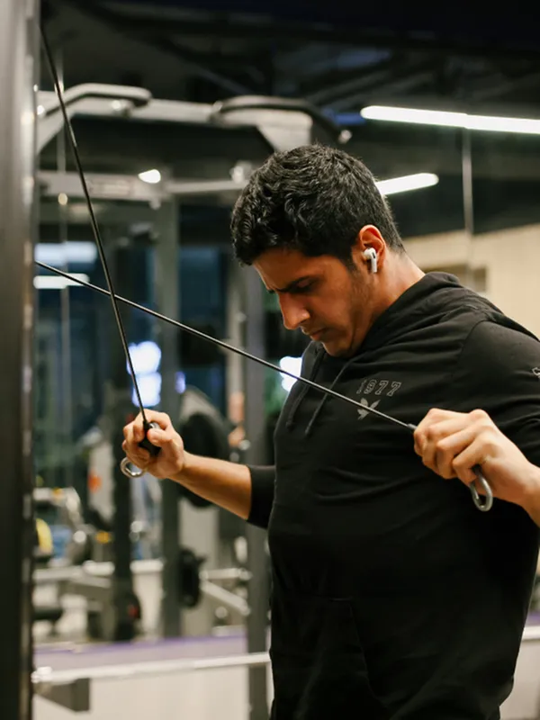 A man uses cable equipment in a modern on-site fitness center, showcasing the community&rsquo;s well-equipped gym for residents.
