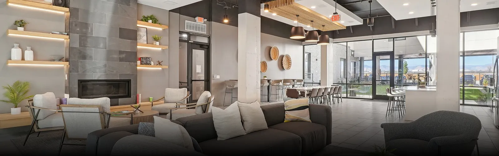 Modern resident lounge featuring cozy seating around a sleek fireplace, open shelving, and large windows overlooking outdoor amenities that highlight the community&rsquo;s upscale social and gathering spaces.