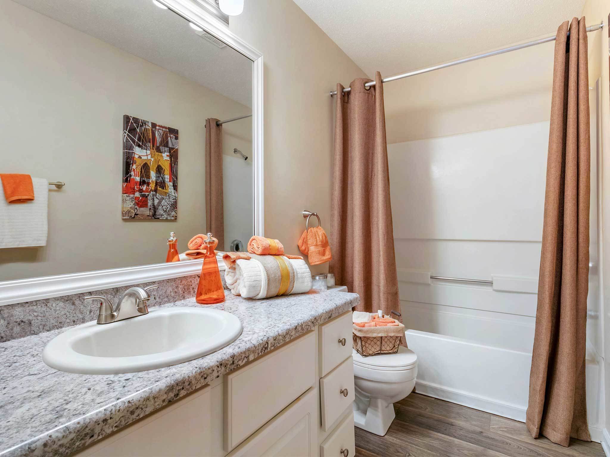 Bathroom with large mirror, bright lighting, tub with shower combination