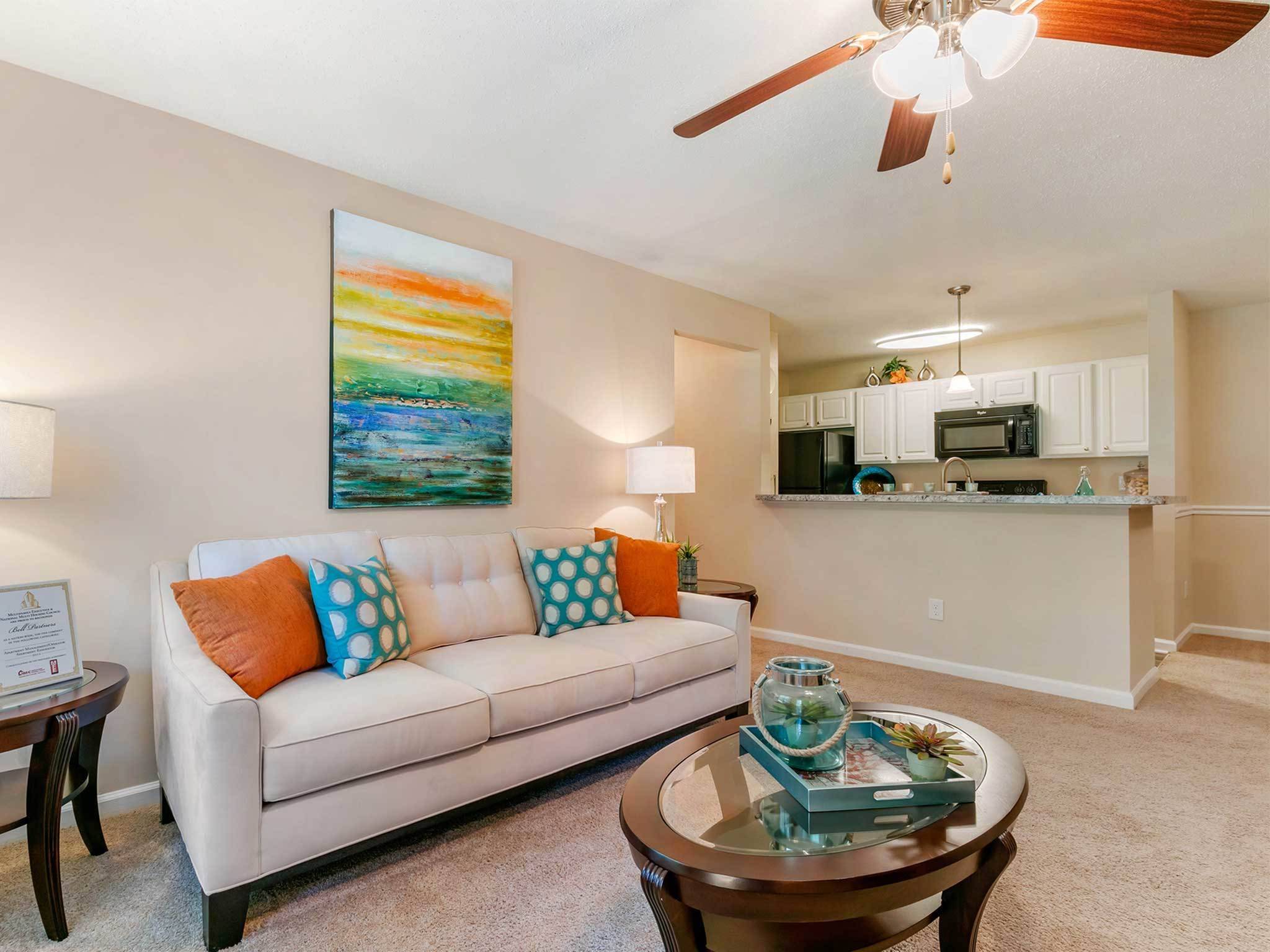 Inviting living room, ceiling fan and light, breakfast bar into kitchen