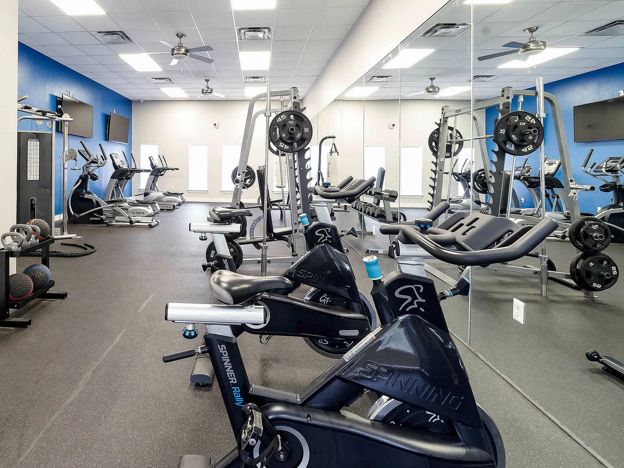 Modern fitness gym with spin bikes, weightlifting equipment, and cardio machines.