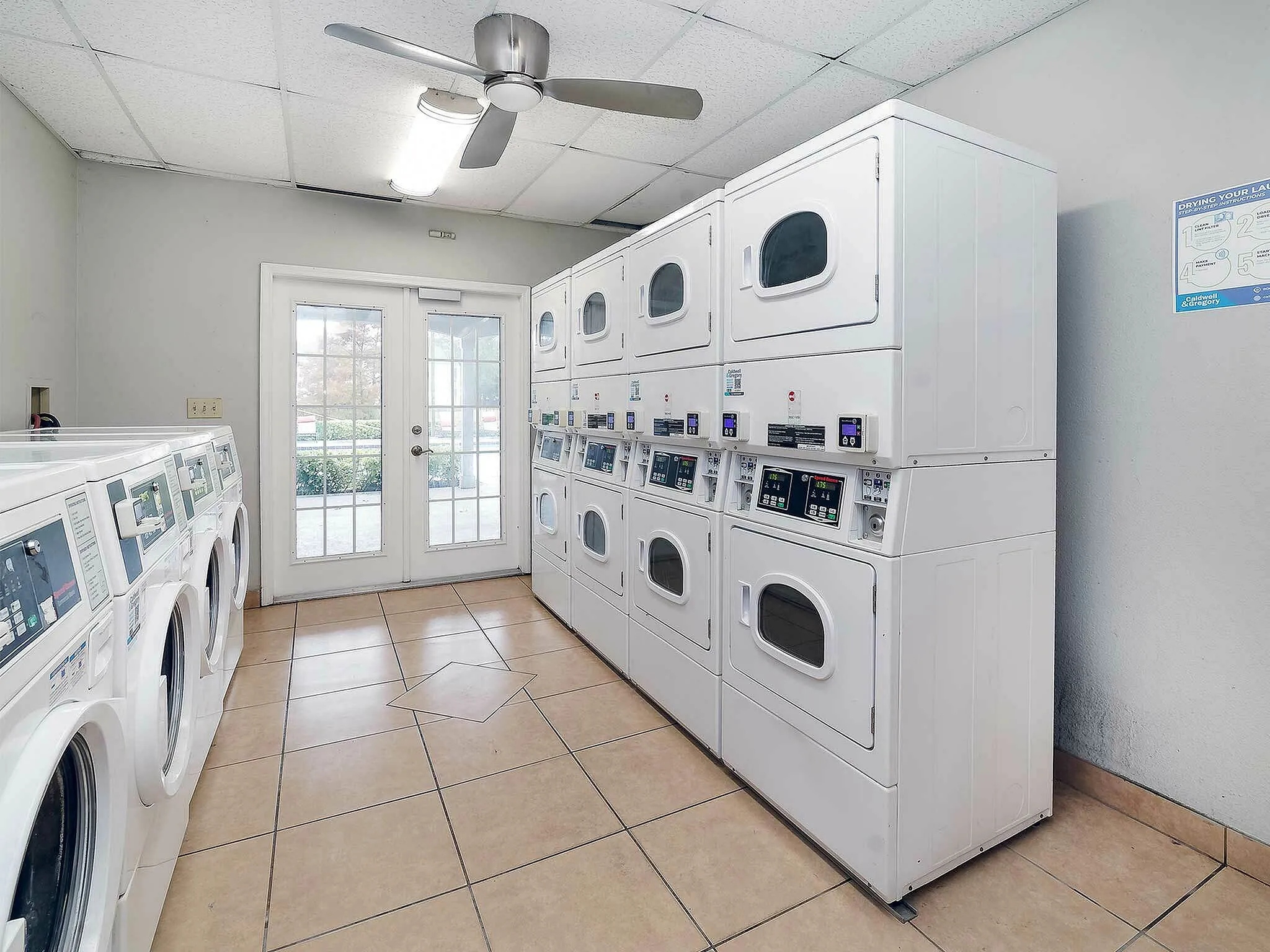 Bright laundry room with multiple washers and dryers, featuring natural lighting and modern design.