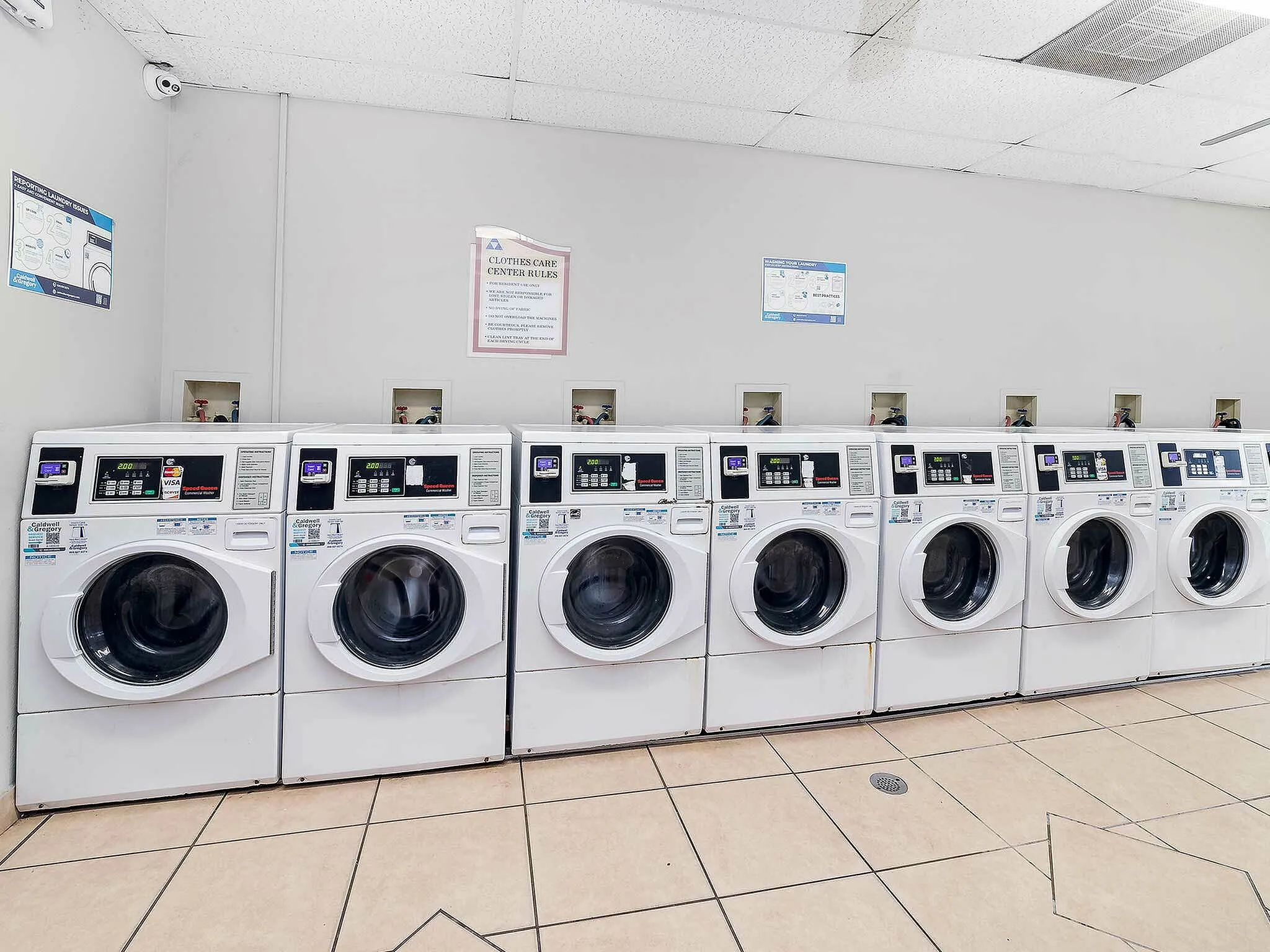 Modern laundry room with a row of eight high-efficiency washing machines in a bright, clean environment.