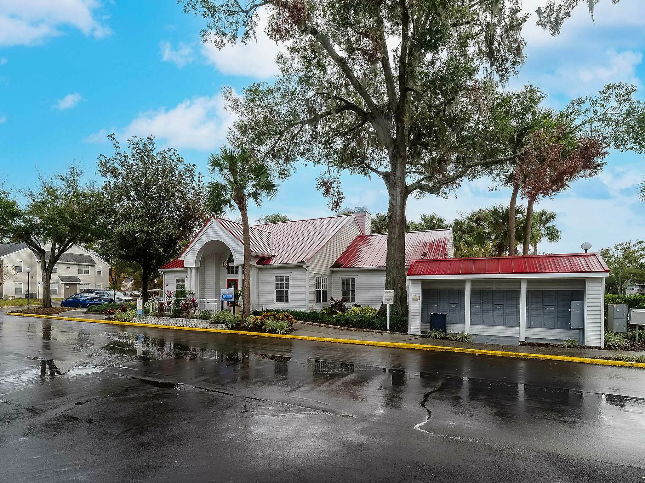 Charming community center with red roof, surrounded by lush trees and vibrant landscaping.