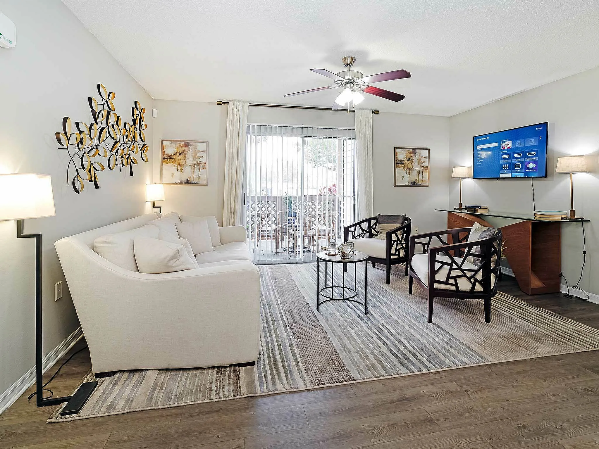 Bright and modern living room with elegant decor, featuring a cozy white sofa, artistic wall art, and a sleek entertainment setup.