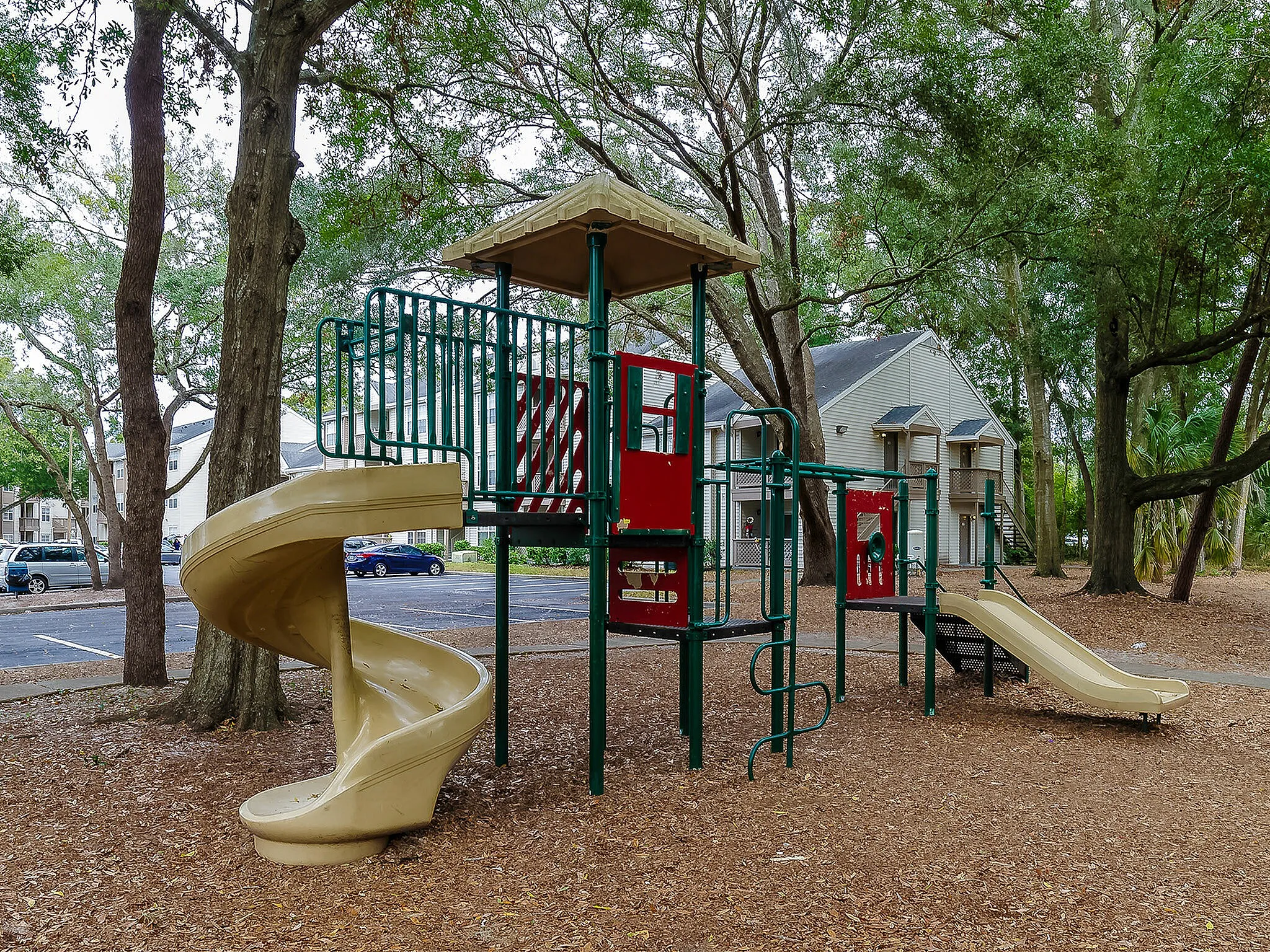 Inviting playground with slides, climbing structures, and surrounded by lush greenery.