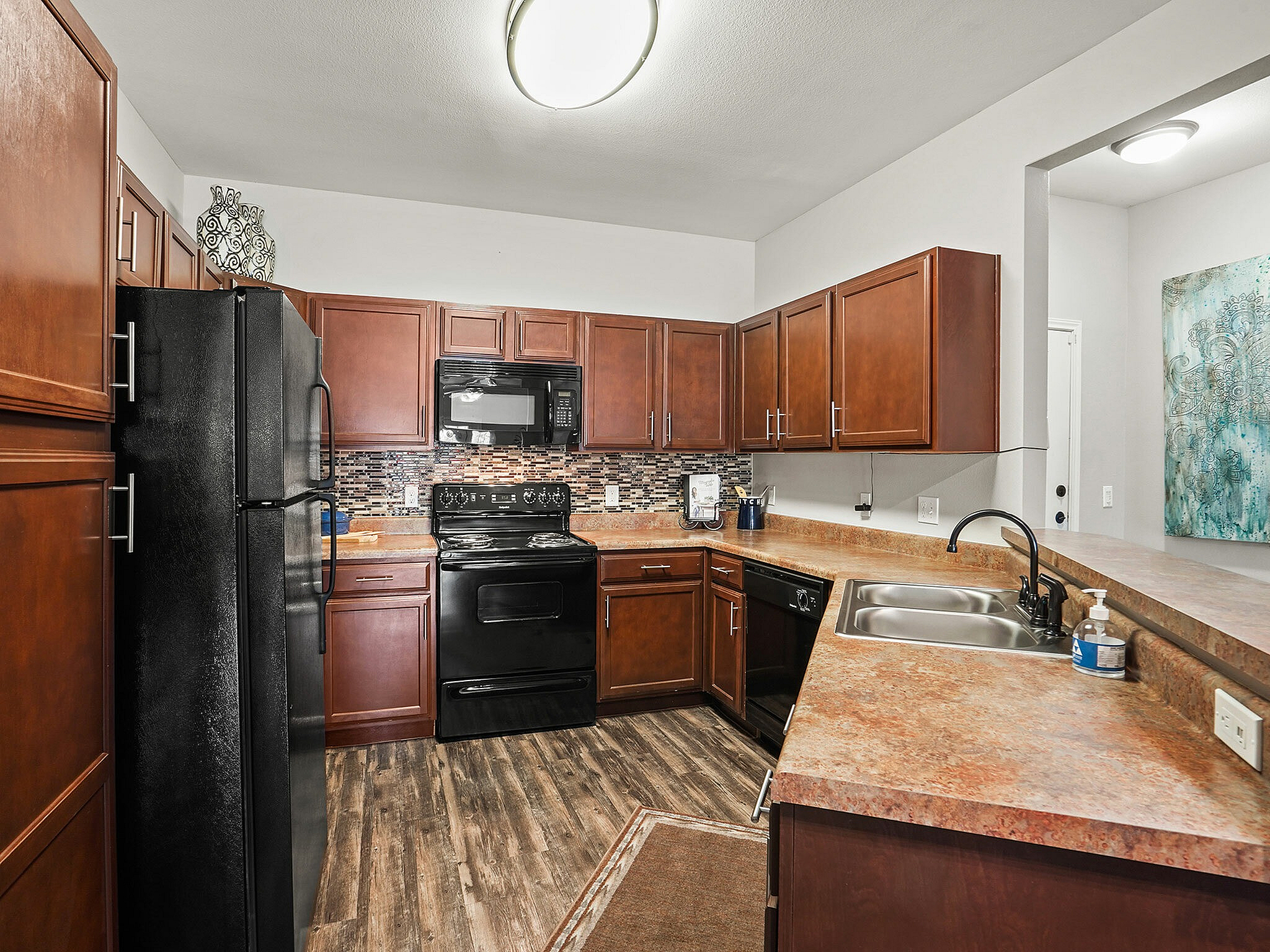 Sleek kitchen featuring modern wood cabinets, black appliances, and a stylish backsplash.