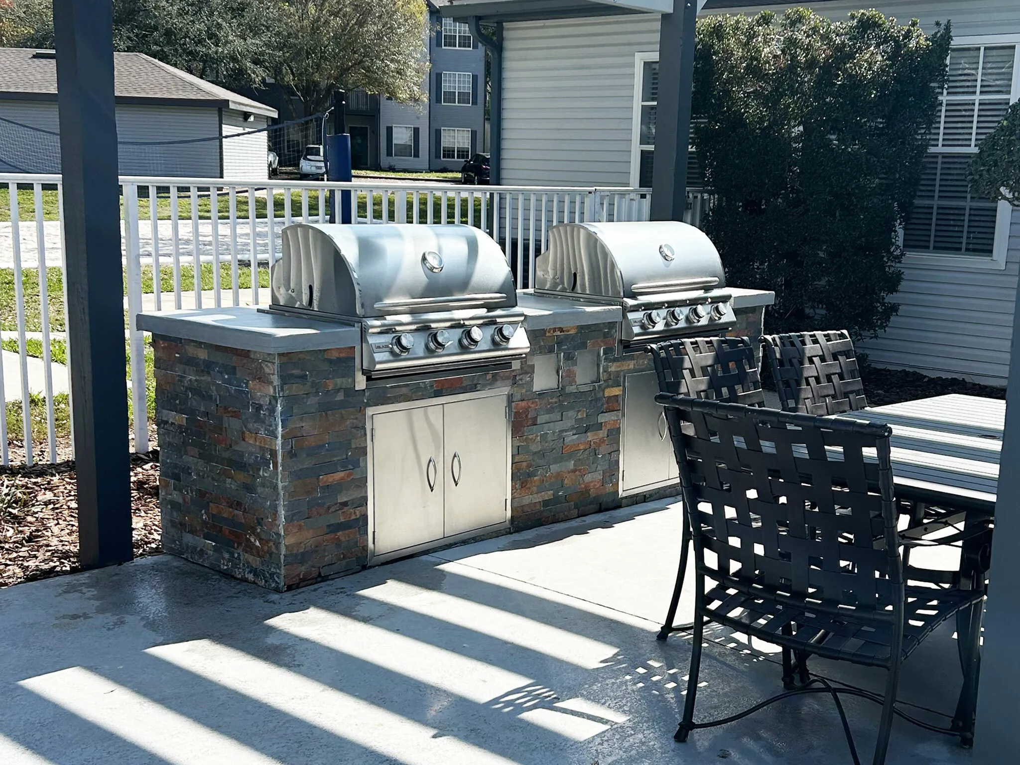 Inviting outdoor barbecue space with two modern grills and stylish seating, perfect for entertaining.
