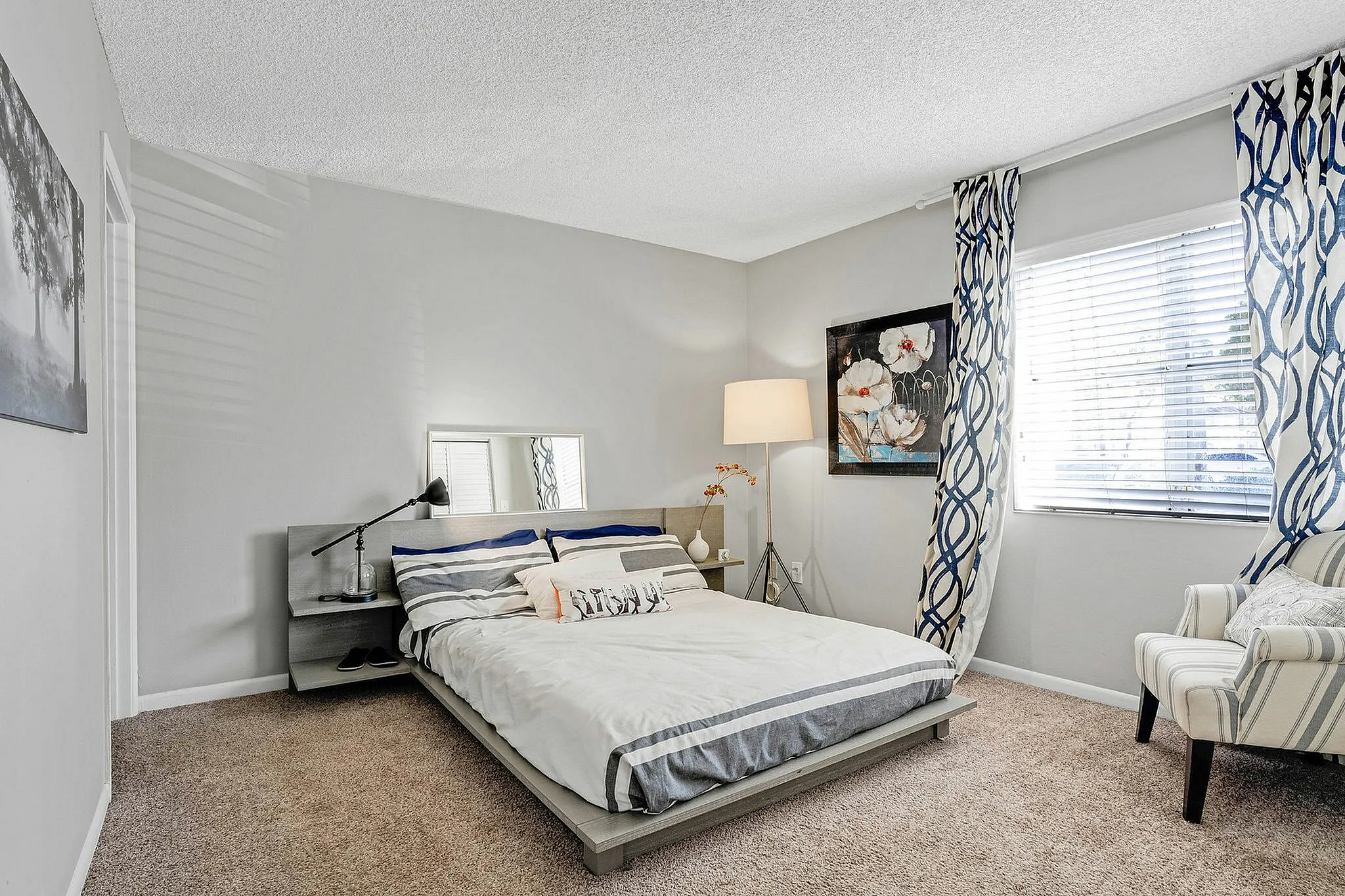 Elegant bedroom with cozy bed, chic striped bedding, stylish decor, and ample natural light.