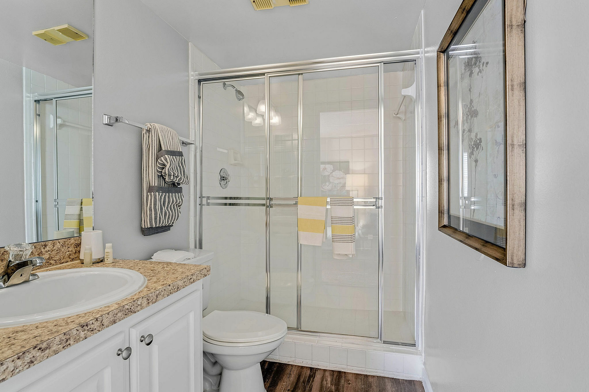 Elegant bathroom showcasing a glass-enclosed shower, granite countertop, and modern fixtures, enhanced by soft lighting and stylish decor.
