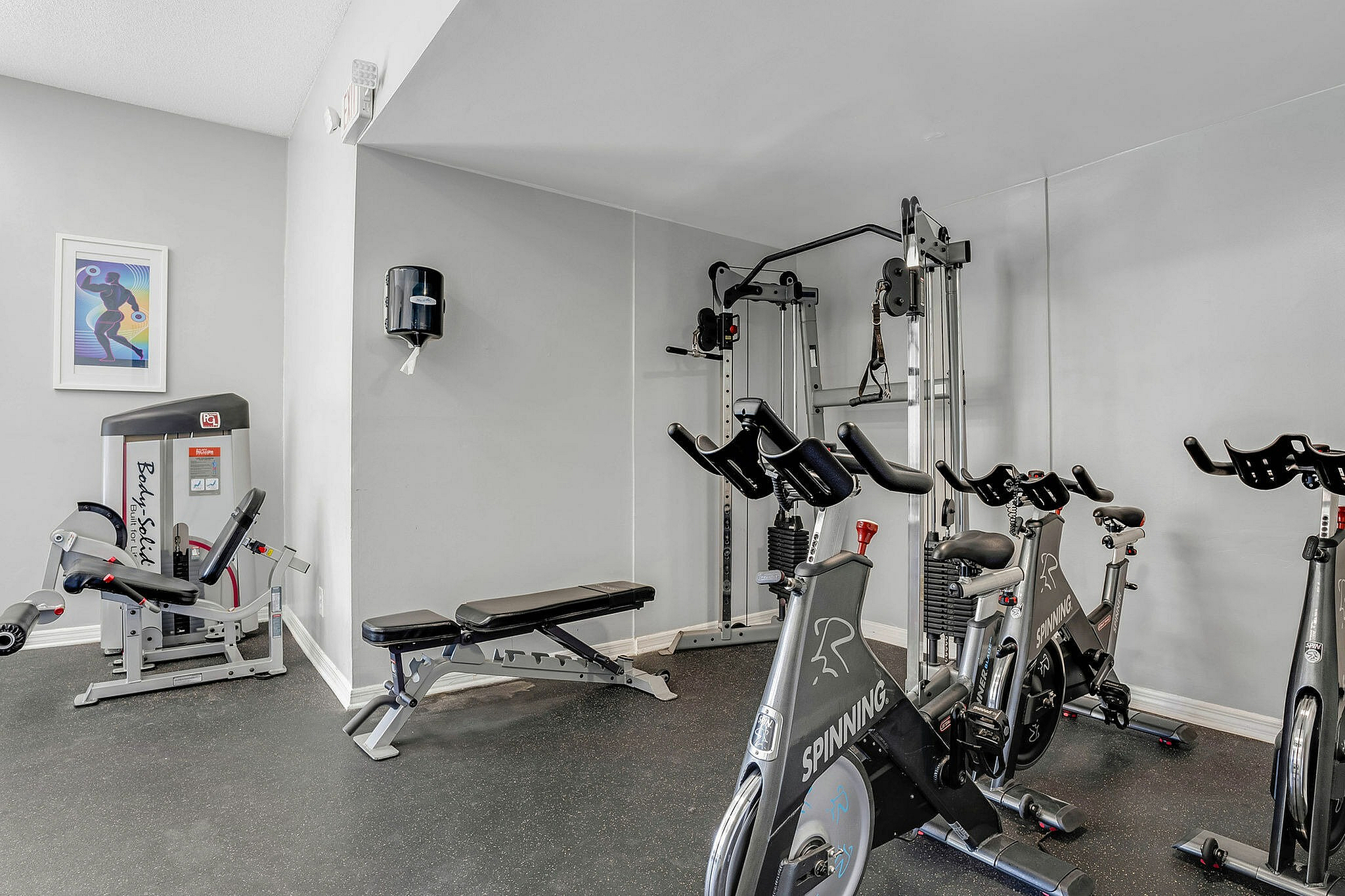 Modern apartment gym featuring spinning bikes, weight bench, and versatile exercise equipment for a complete workout experience.