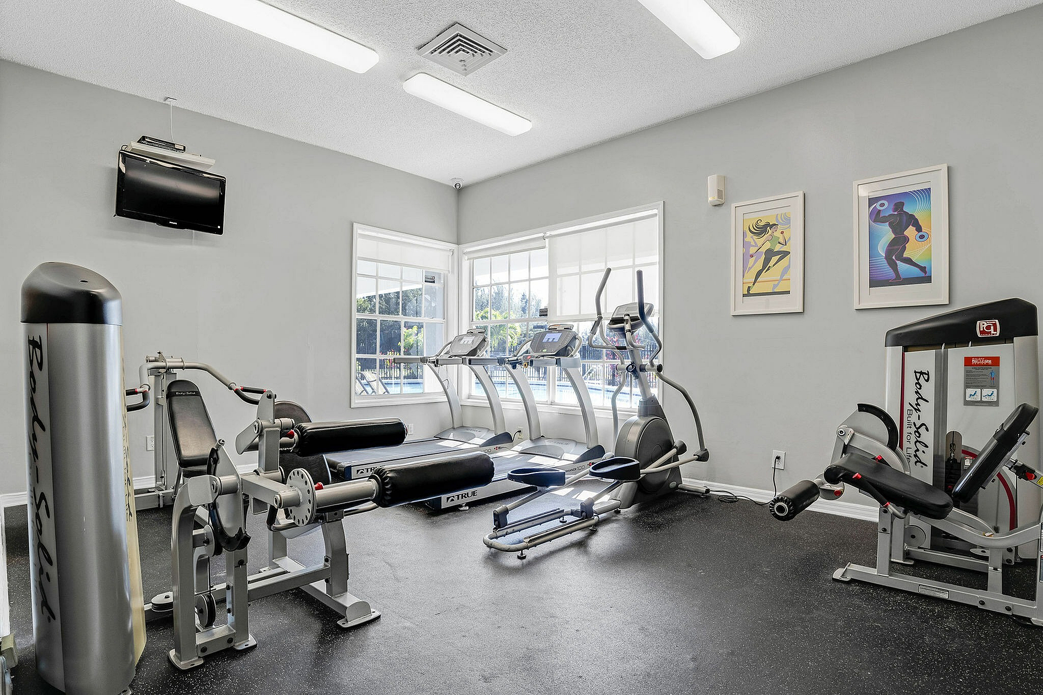 Bright and modern apartment fitness center with state-of-the-art gym equipment and large windows overlooking serene outdoor views.