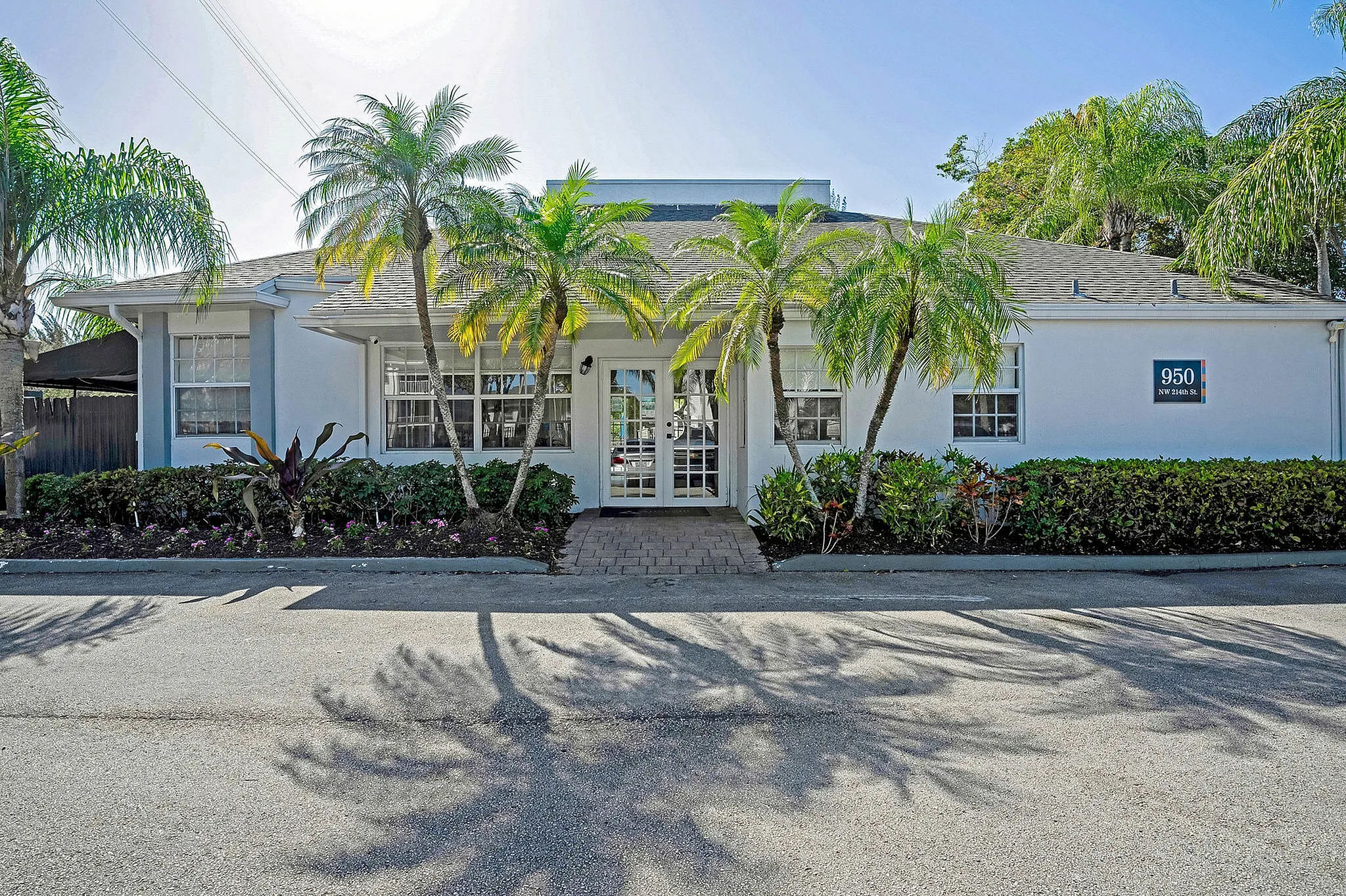 Charming white house with lush palm trees and manicured landscaping, creating a welcoming and tropical ambiance.