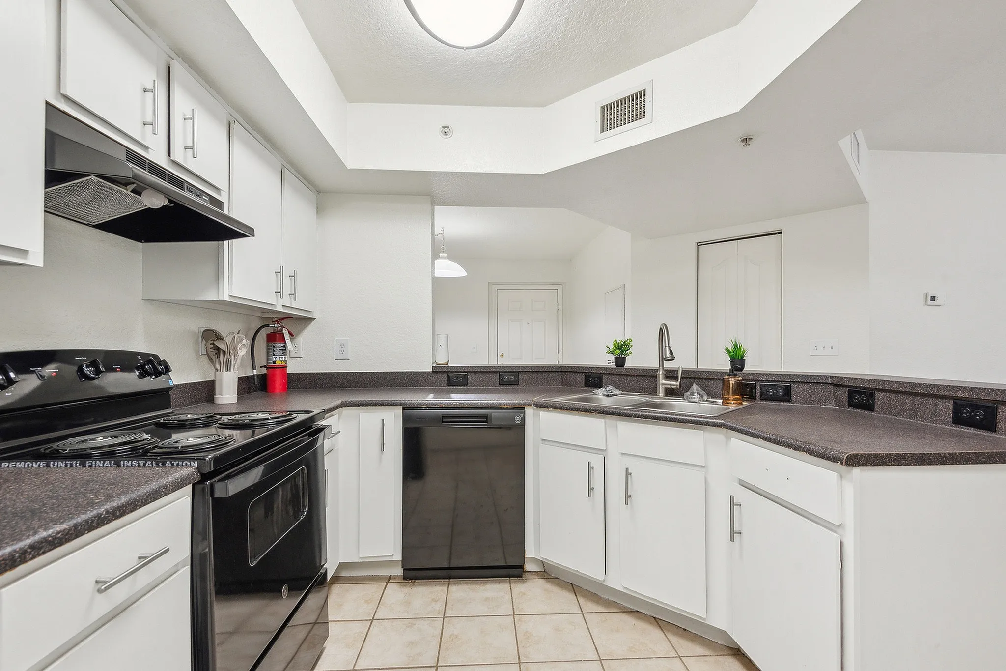 Modern kitchen with sleek black appliances, ample counter space, and stylish white cabinetry. Bright and inviting layout perfect for culinary enthusiasts.