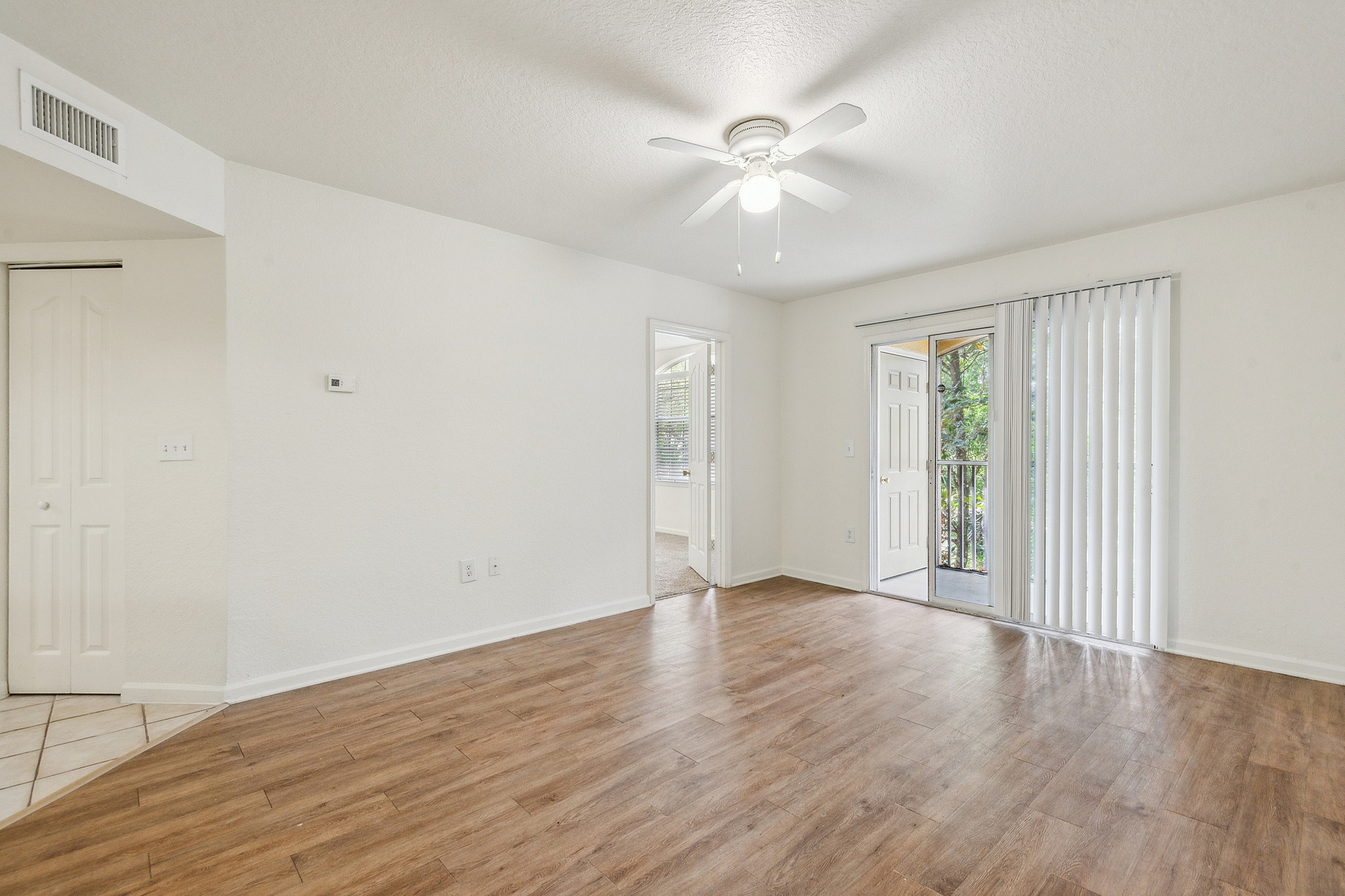Bright and airy living room with elegant wood flooring and natural light from sliding glass doors.