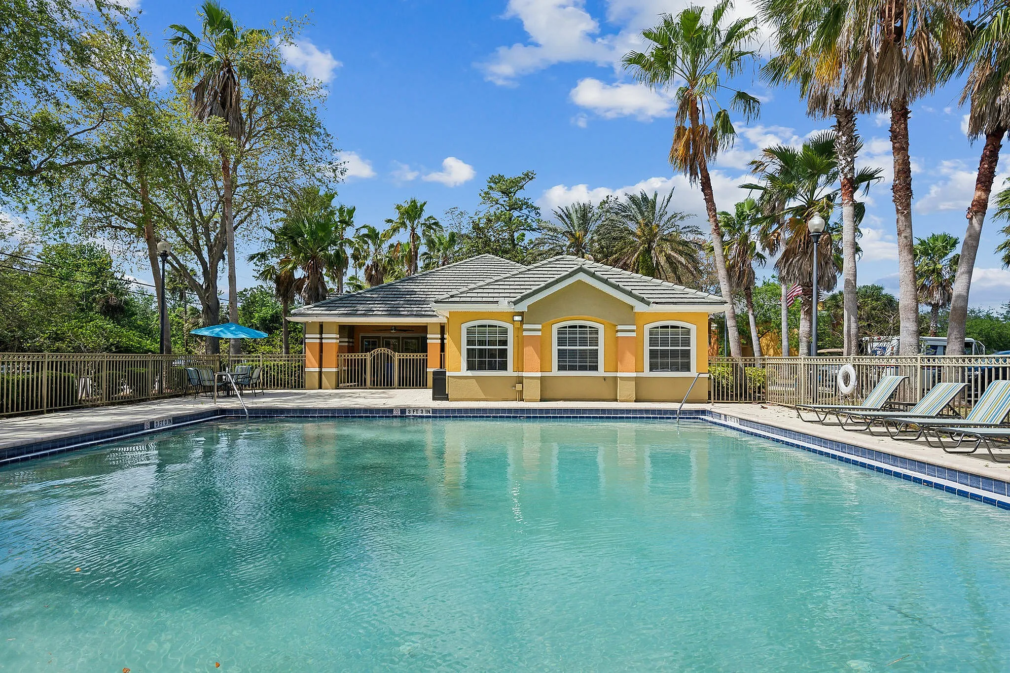 Inviting swimming pool surrounded by palm trees and sun loungers, perfect for relaxation in a tranquil environment.