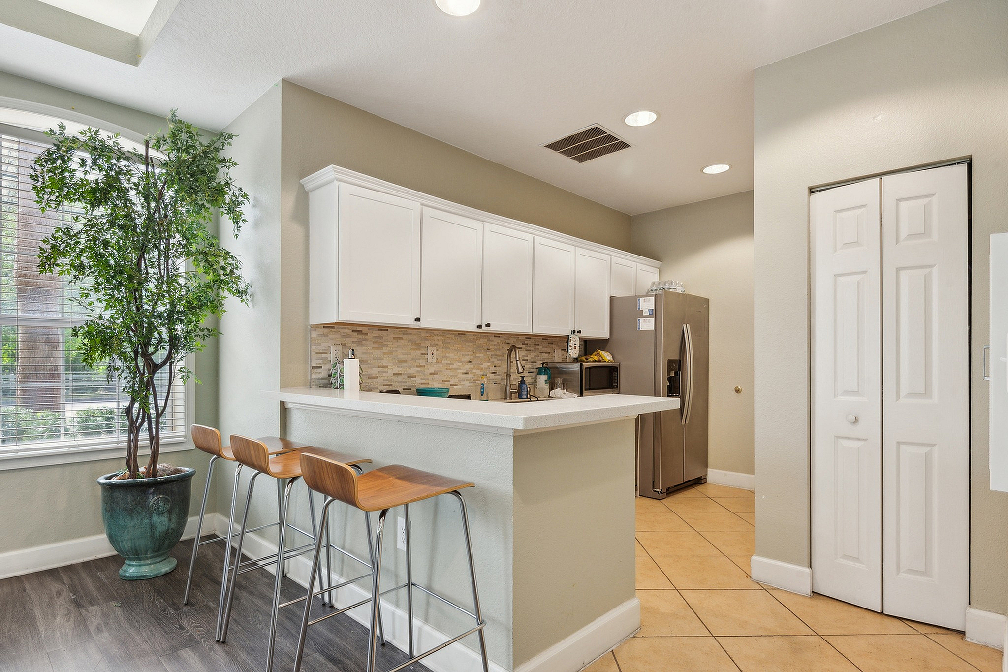 Bright and inviting kitchen with sleek white cabinets, a stylish tile backsplash, and a cozy breakfast bar with modern bar stools.