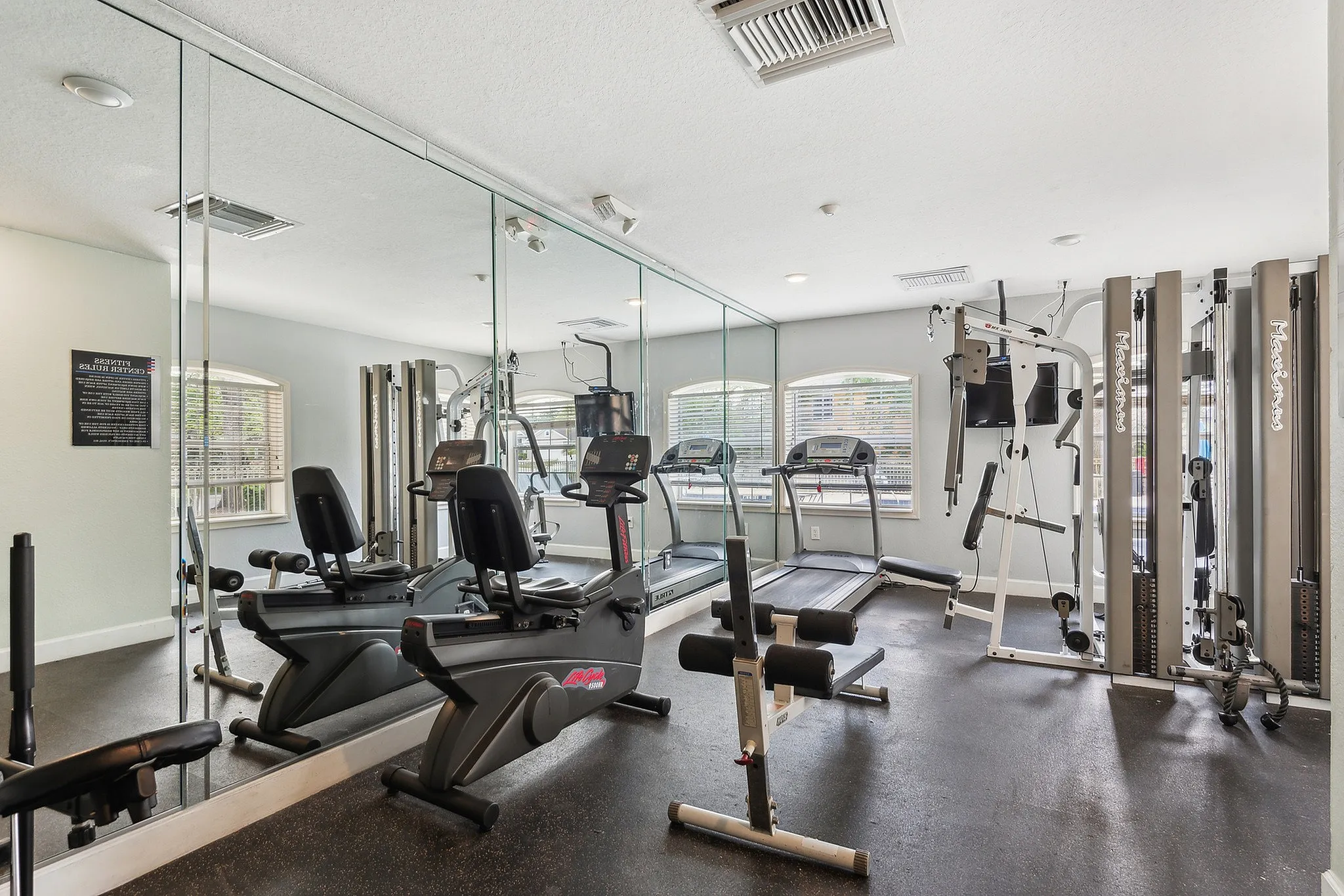 Modern fitness center with state-of-the-art equipment, mirrored walls, and large windows for natural light.