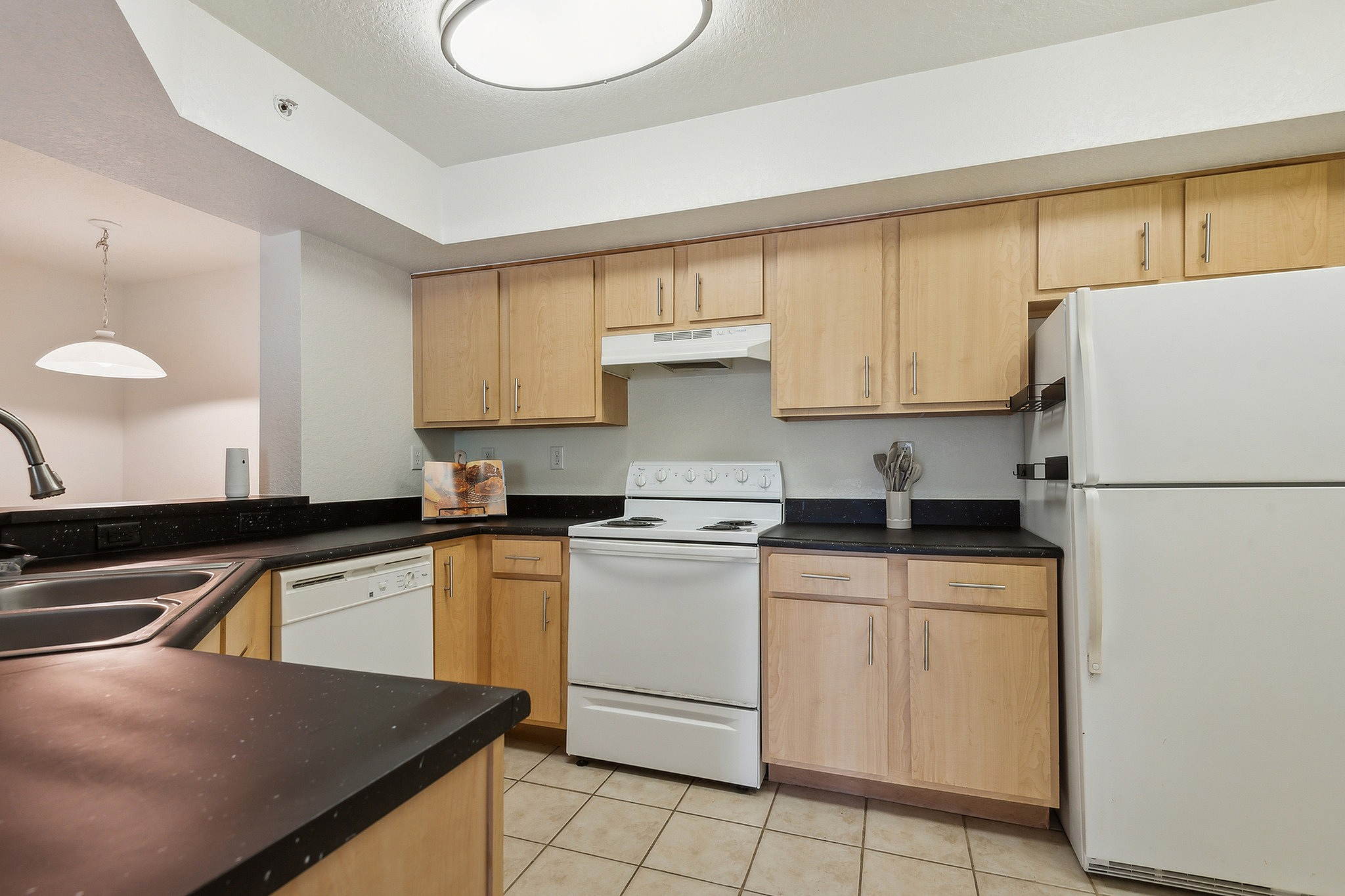 Modern kitchen with sleek black countertops, ample wooden cabinetry, and essential appliances for an ideal cooking space.