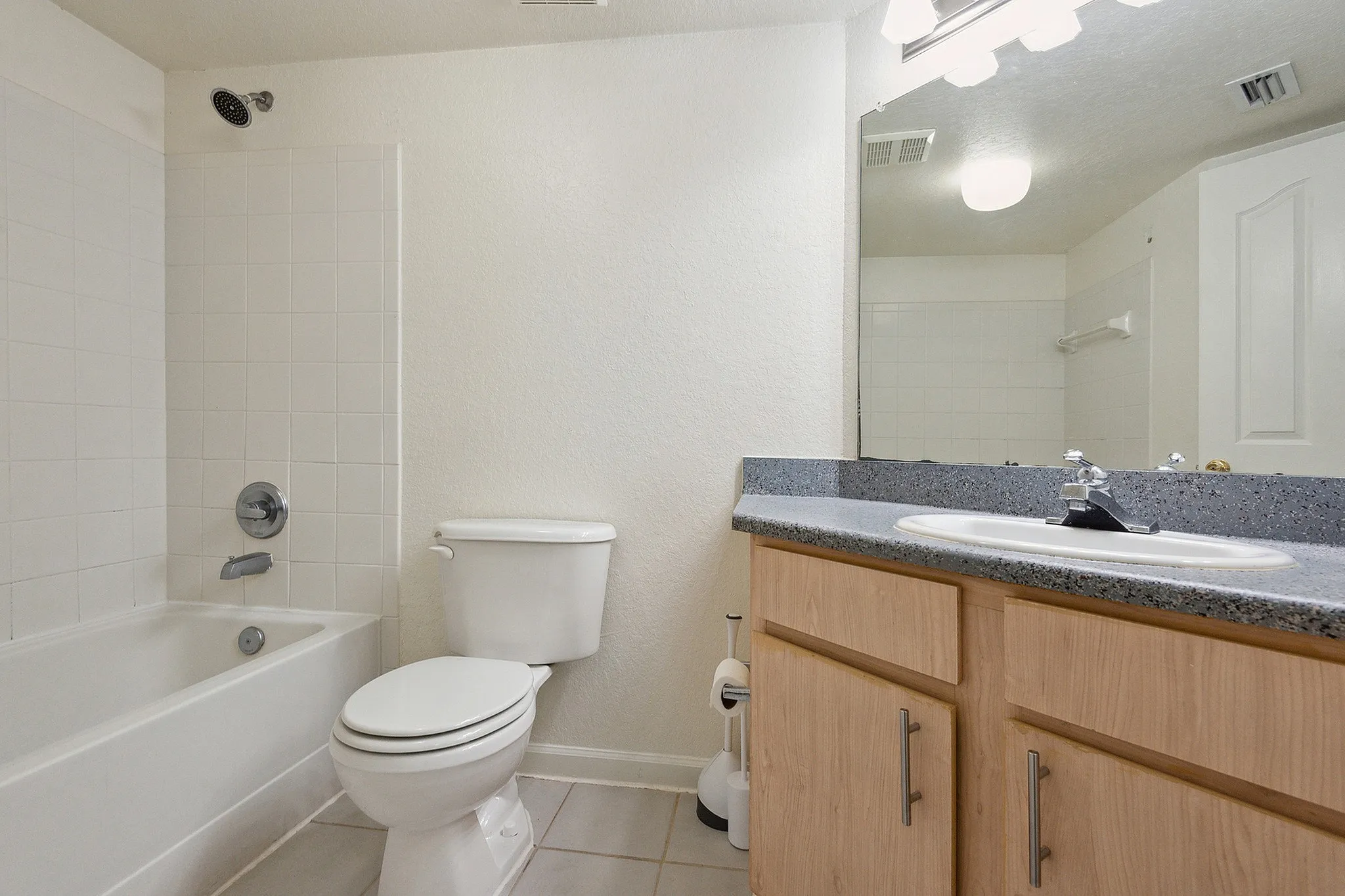 Bright and modern bathroom featuring a sleek vanity with granite countertop, classic white tile bathtub, and contemporary lighting.