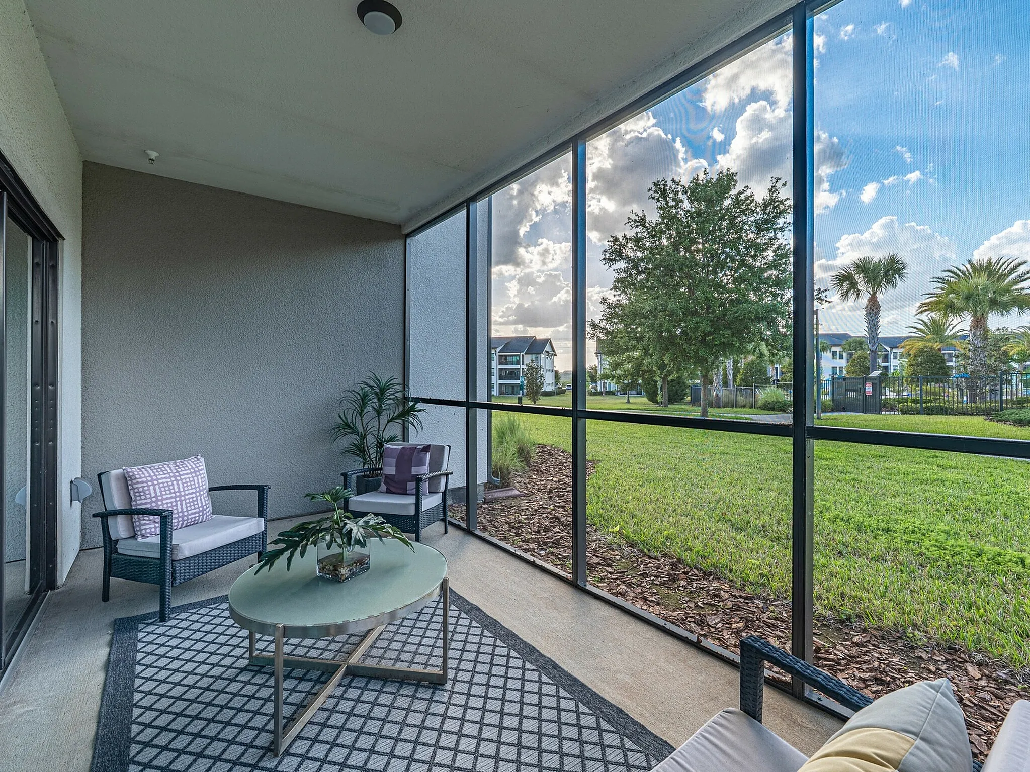 Charming enclosed patio with stylish seating and stunning views of lush green landscape and palm trees.