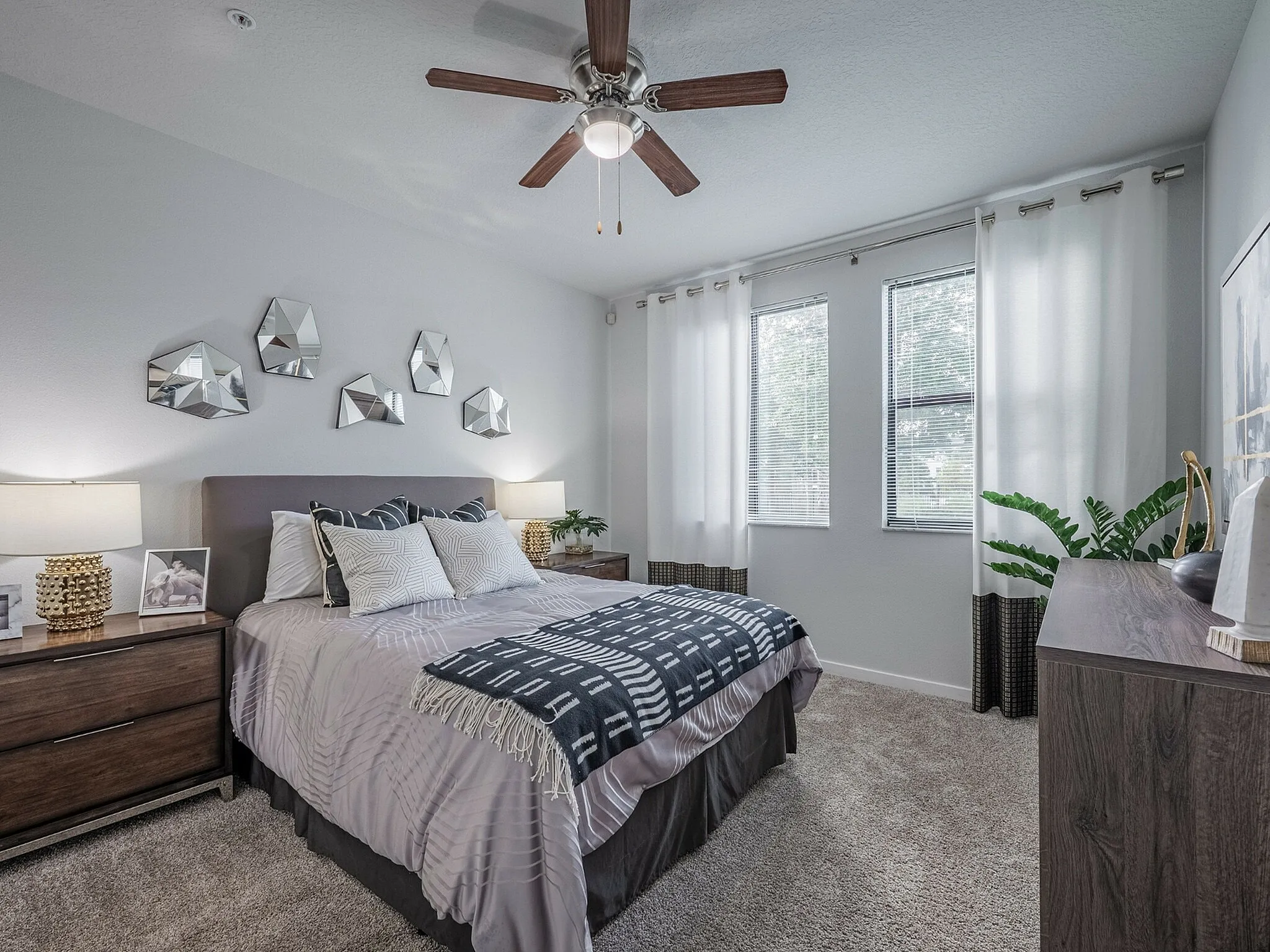Elegant bedroom with modern decor, featuring a plush bed, stylish mirrors on the wall, and large windows inviting natural light.