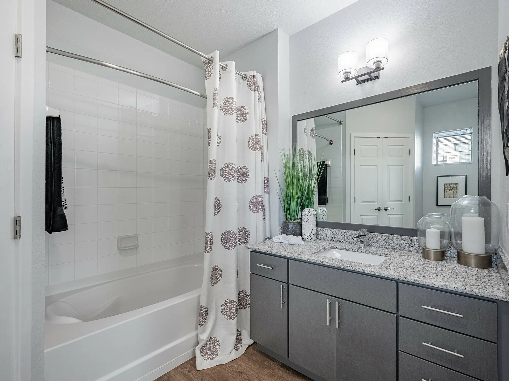 Modern bathroom with elegant granite countertop, sleek cabinetry, and a stylish bathtub with patterned shower curtain.