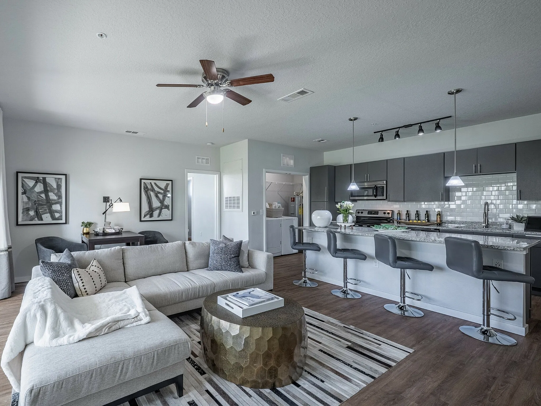 Modern open-concept living space with a sleek kitchen, stylish bar stools, and cozy sectional sofa, perfect for entertaining.