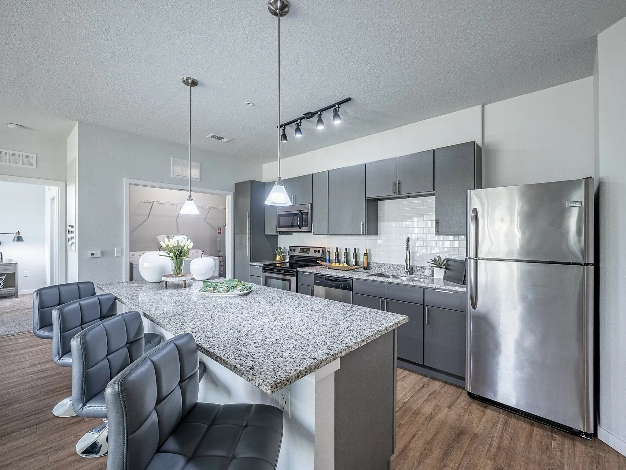 Modern kitchen with sleek gray cabinetry, stainless steel appliances, and a granite island with chic bar seating, perfect for entertaining.