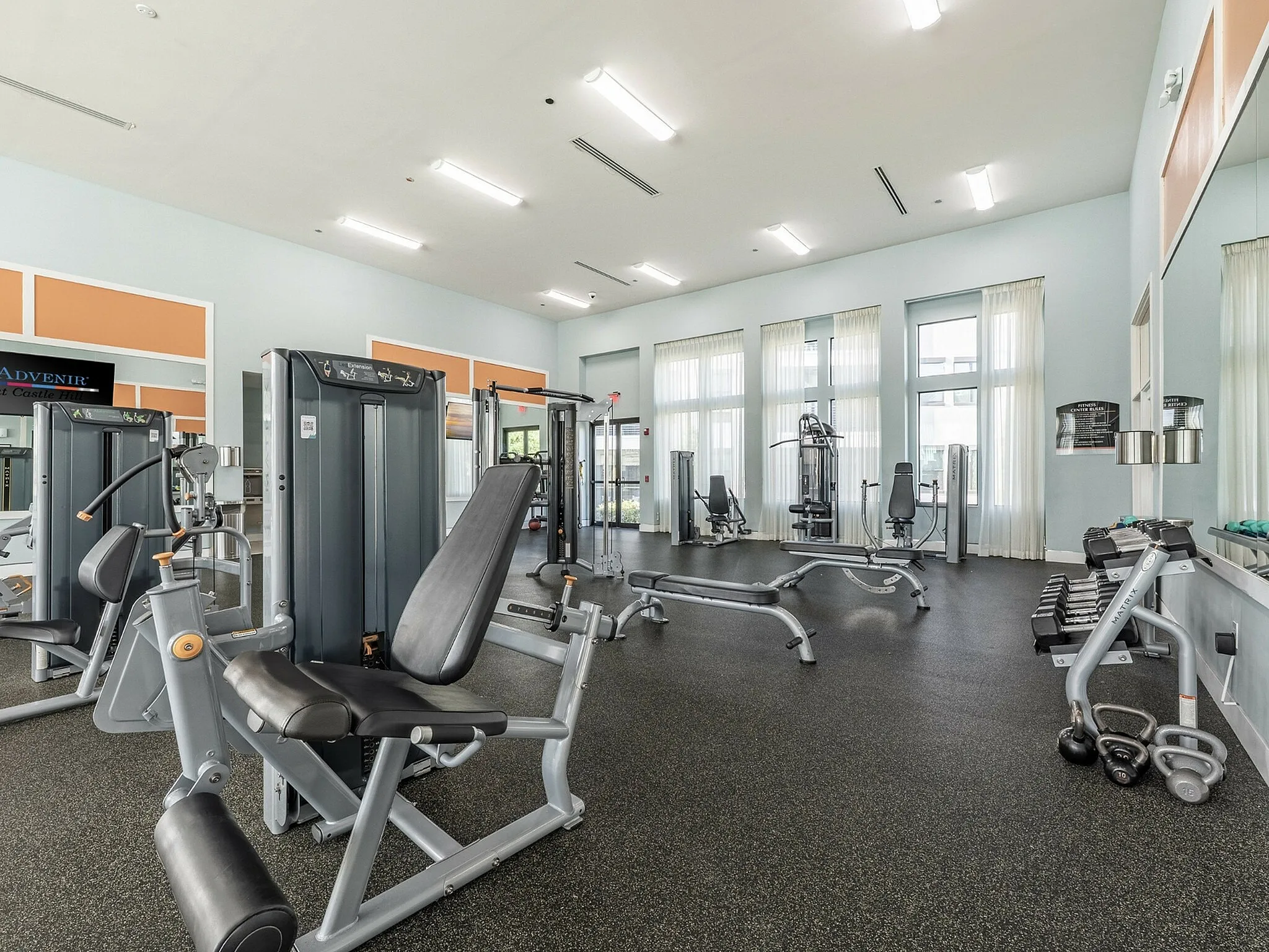 Bright and spacious fitness center with modern exercise equipment and large windows for natural light.