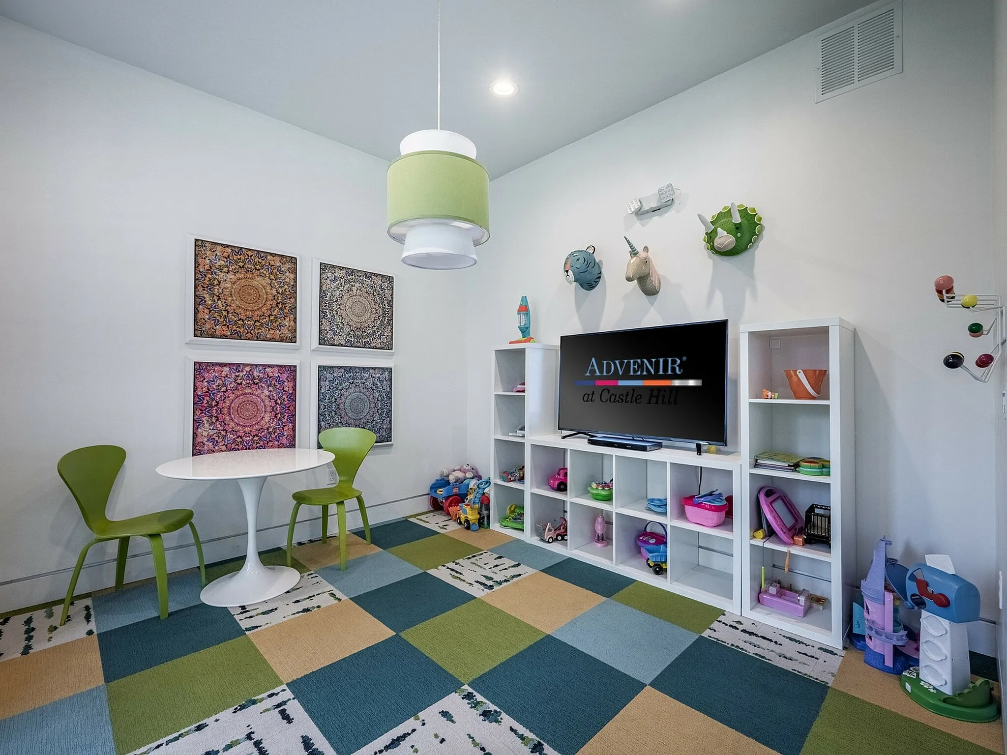 Vibrantly decorated children's playroom with colorful flooring, art-adorned walls, and playful storage shelves at Advenir at Castle Hill.