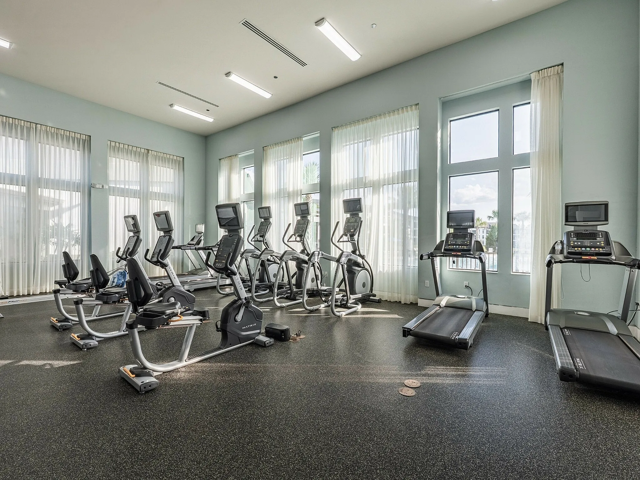 Bright and spacious gym with modern exercise equipment, large windows, and welcoming atmosphere.