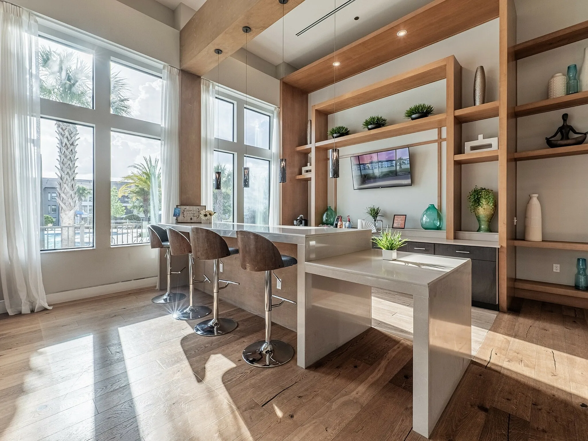 Bright and modern kitchen space with a large island, stylish bar stools, and natural light streaming through tall windows, complemented by elegant shelving and chic decor.