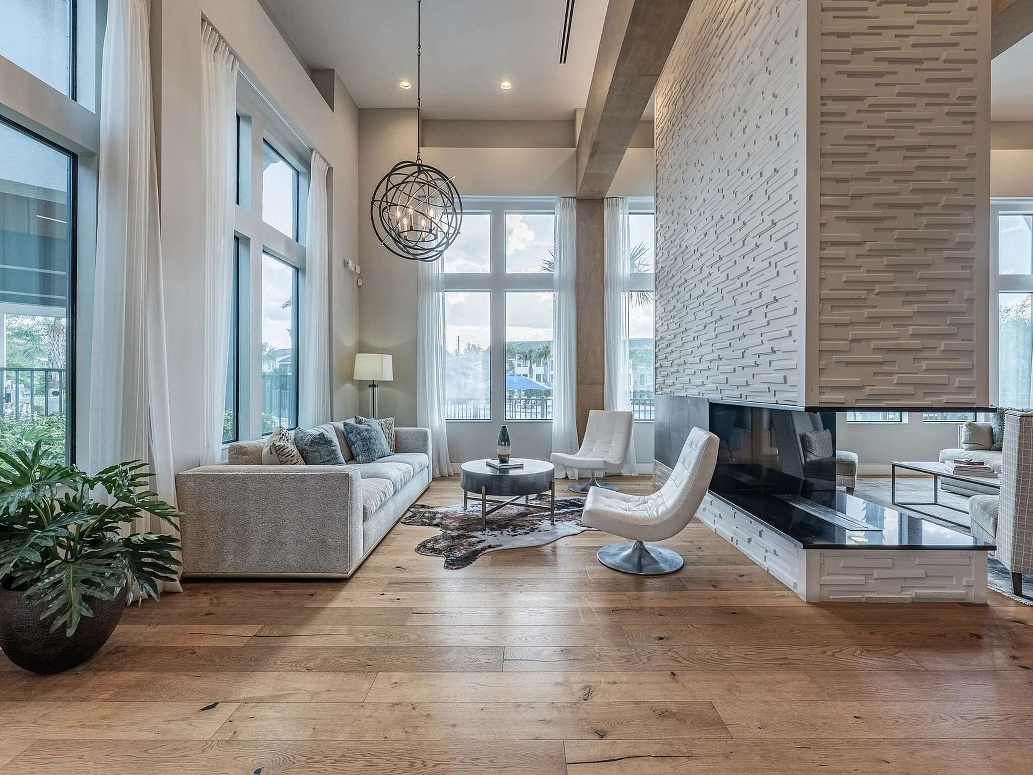 Luxurious open living area with elegant furnishings, modern fireplace, and floor-to-ceiling windows offering abundant natural light.