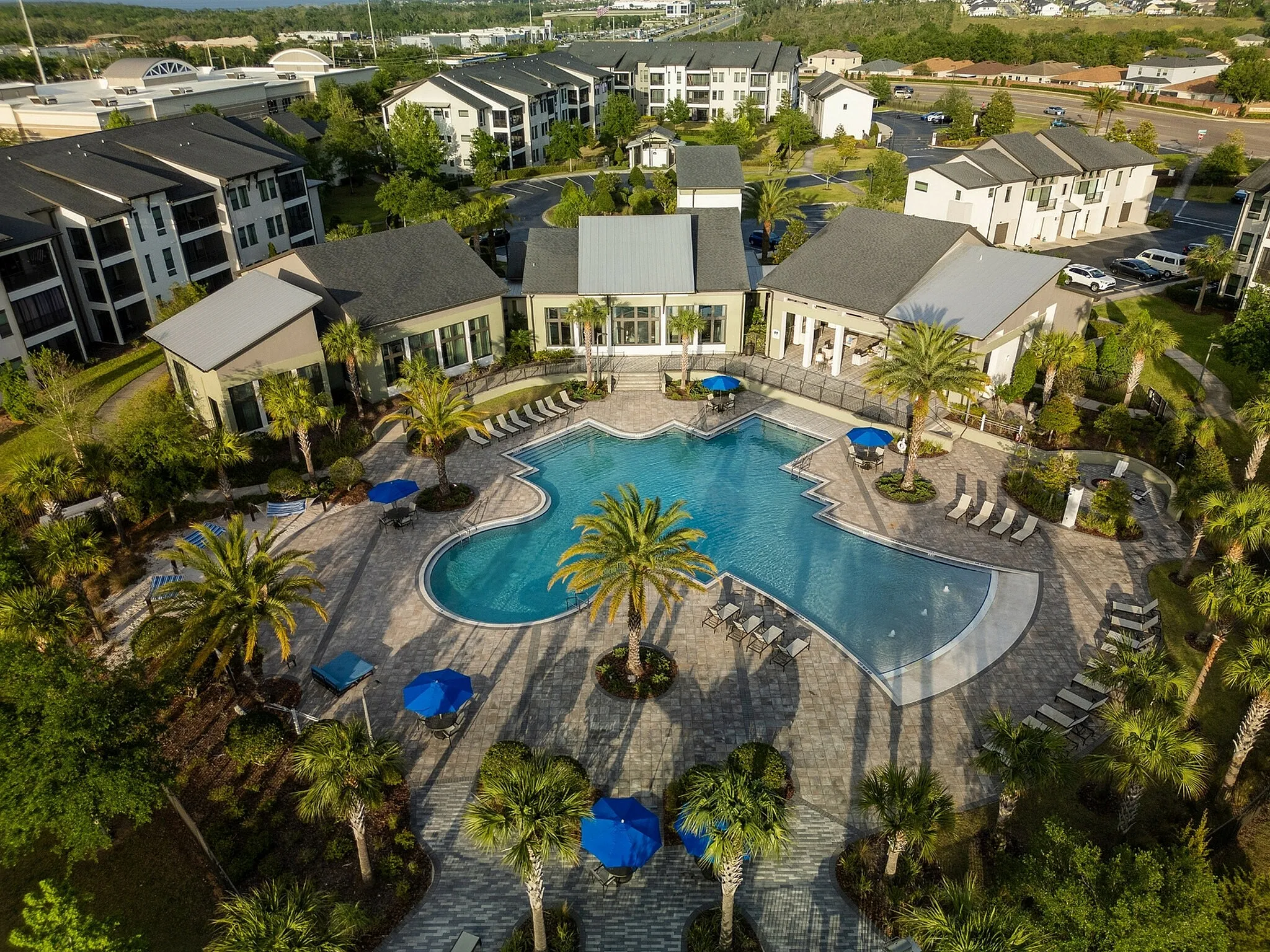 Luxurious apartment complex featuring a resort-style pool, surrounded by palm trees and scenic landscaping, offering a serene and picturesque living experience.