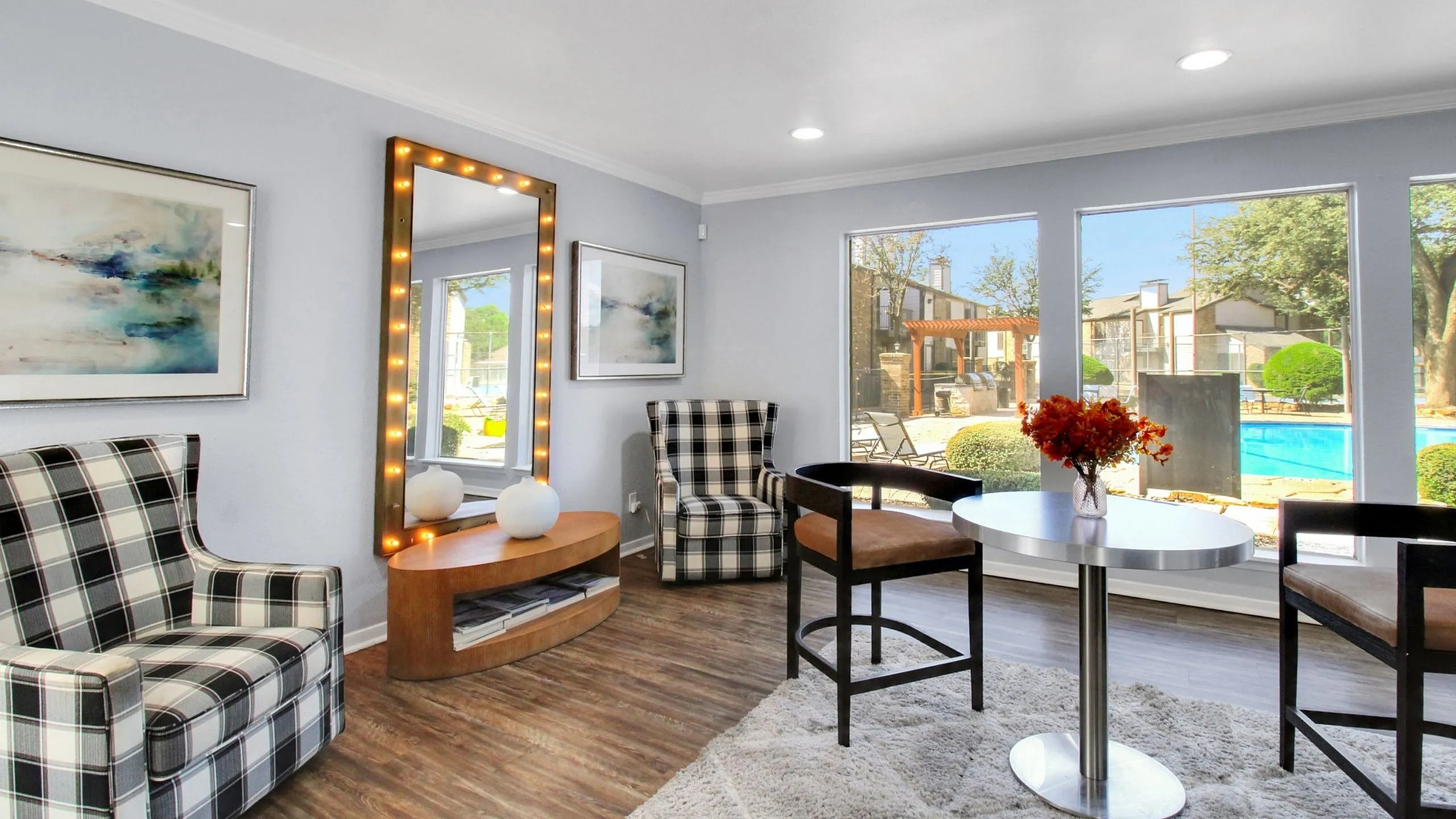 Chic lounge area with modern decor, large windows overlooking a stunning pool and landscaped courtyard, perfect for relaxation and socializing.