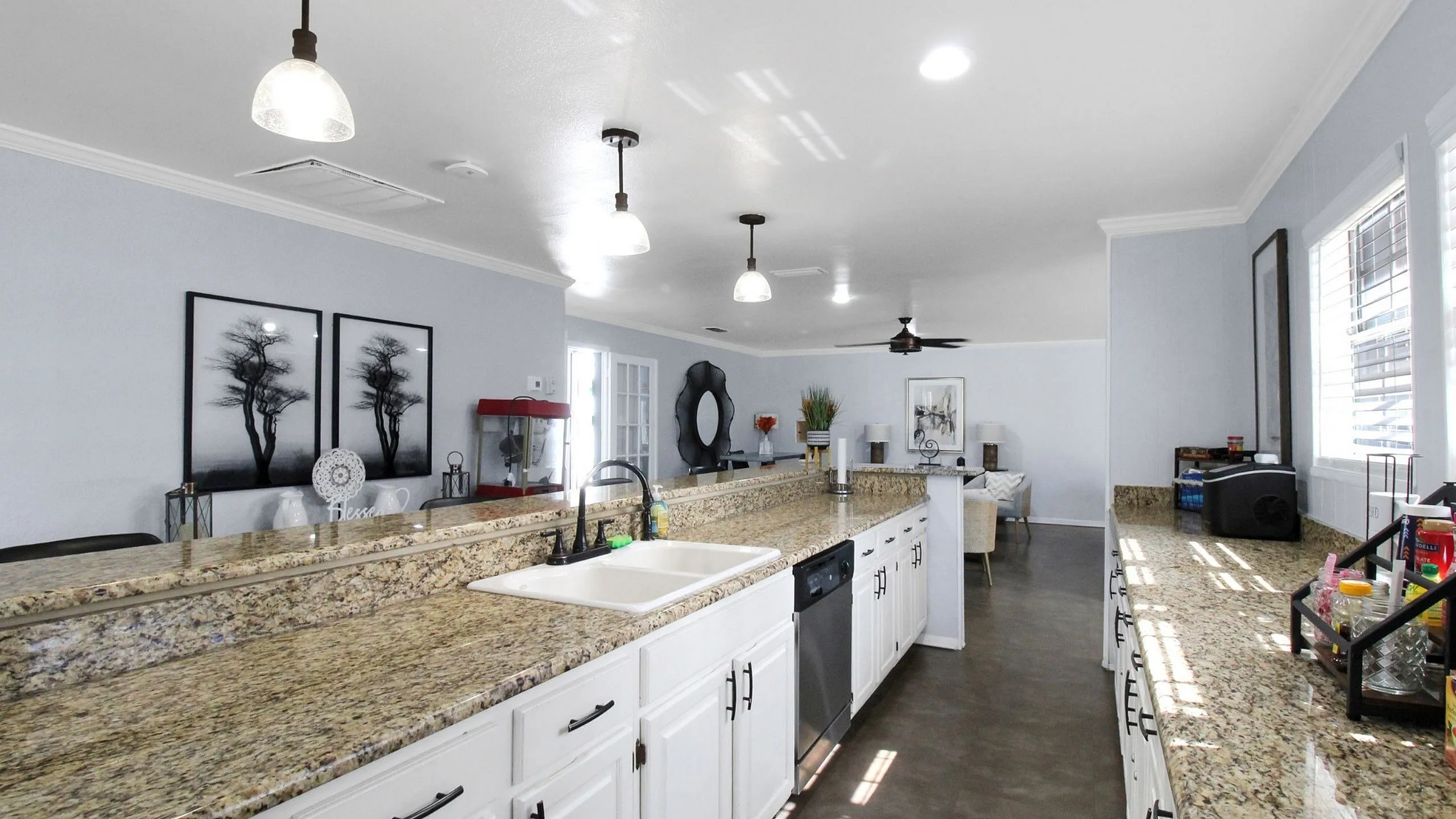 Spacious and modern kitchen with granite countertops, stylish pendant lighting, and open floor plan leading to a cozy living area.