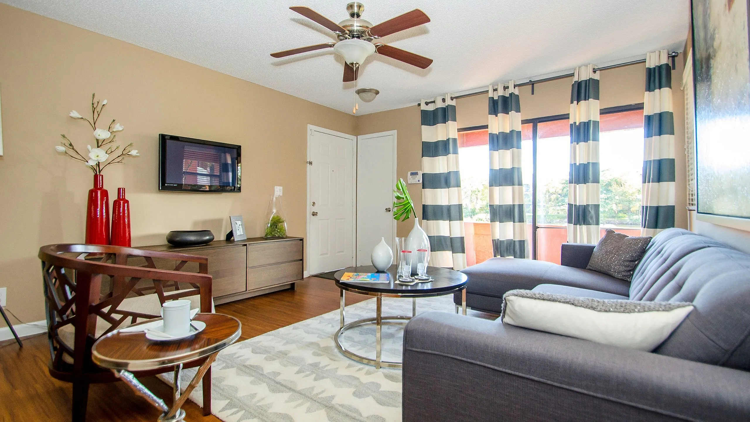 Inviting living room with chic decor, featuring a plush gray sofa, elegant wooden chair, and a stylish round coffee table accented with vibrant red vases.