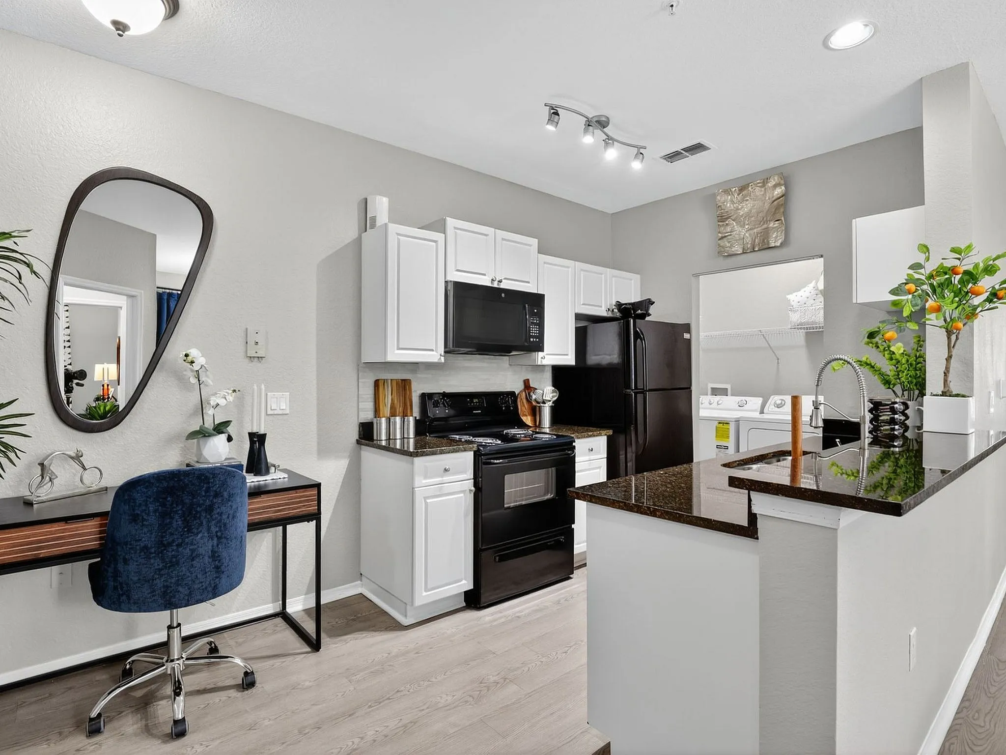 Chic modern kitchen with sleek black appliances, elegant granite countertops, a compact office nook, and fresh decor.