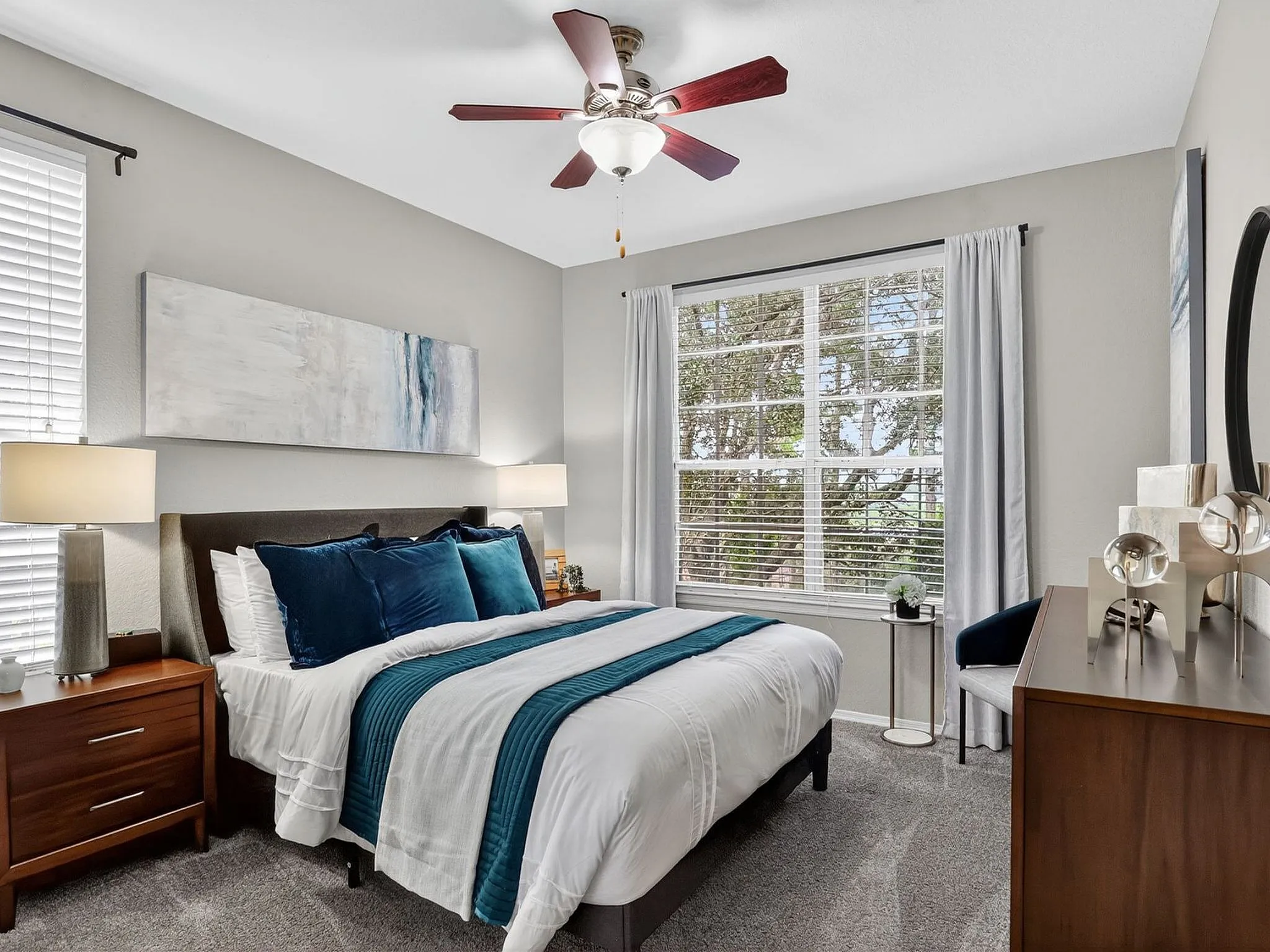 Inviting bedroom with elegant decor, soft lighting, and large window offering a scenic view, perfect for relaxation.